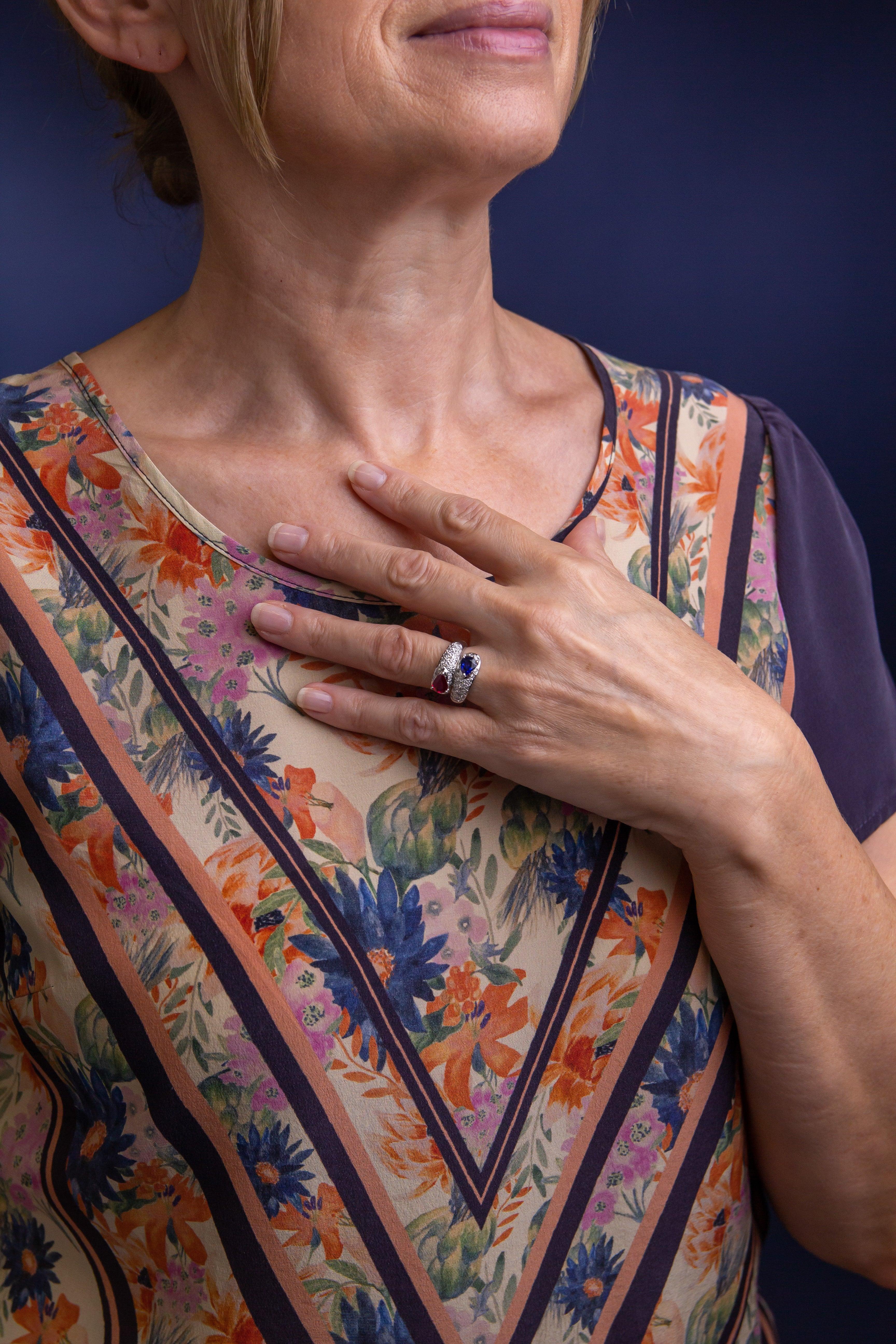 Cette bague « bypass » est fabriquée en or blanc 18 carats et a été sertie de diamants, d'un saphir et d'un rubis. La tige légèrement effilée s'enroule autour du doigt et se termine à chaque extrémité par un rubis dans l'un et un saphir dans