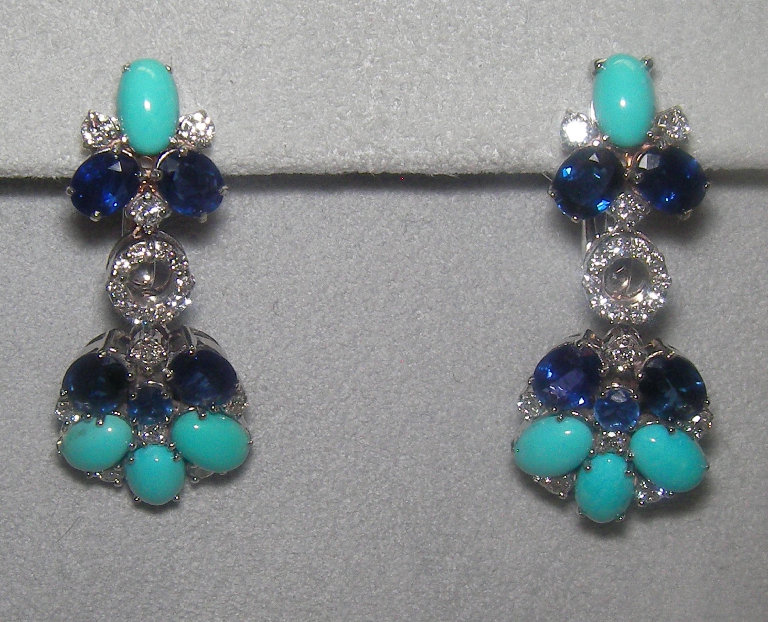 These stunning 18 Karat White Gold Diamond, Sapphire, and Turquoise Dangle Earrings feature an array of cabochon recon turquoise and oval and rounded cut sapphire. These earrings go perfectly with our 18 Karat White Gold Diamond, Sapphire, and