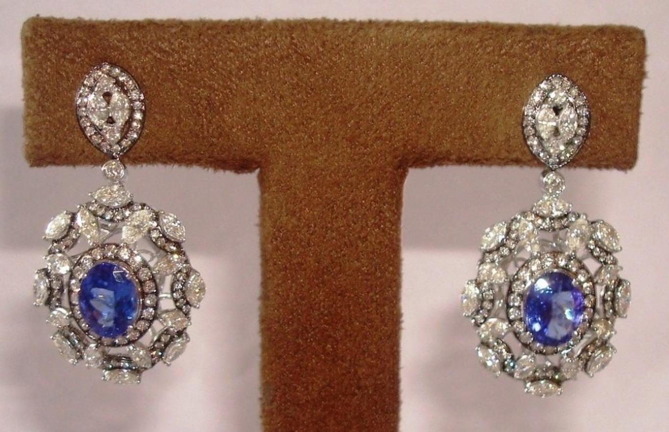 These linear earrings are studded with a beautiful oval cut tanzanite as a centre stone. Brilliant cut round & marquise shape diamonds compliment the tanzanite. The back of the earrings is a plain gold mirror image of the front & the entire bottom