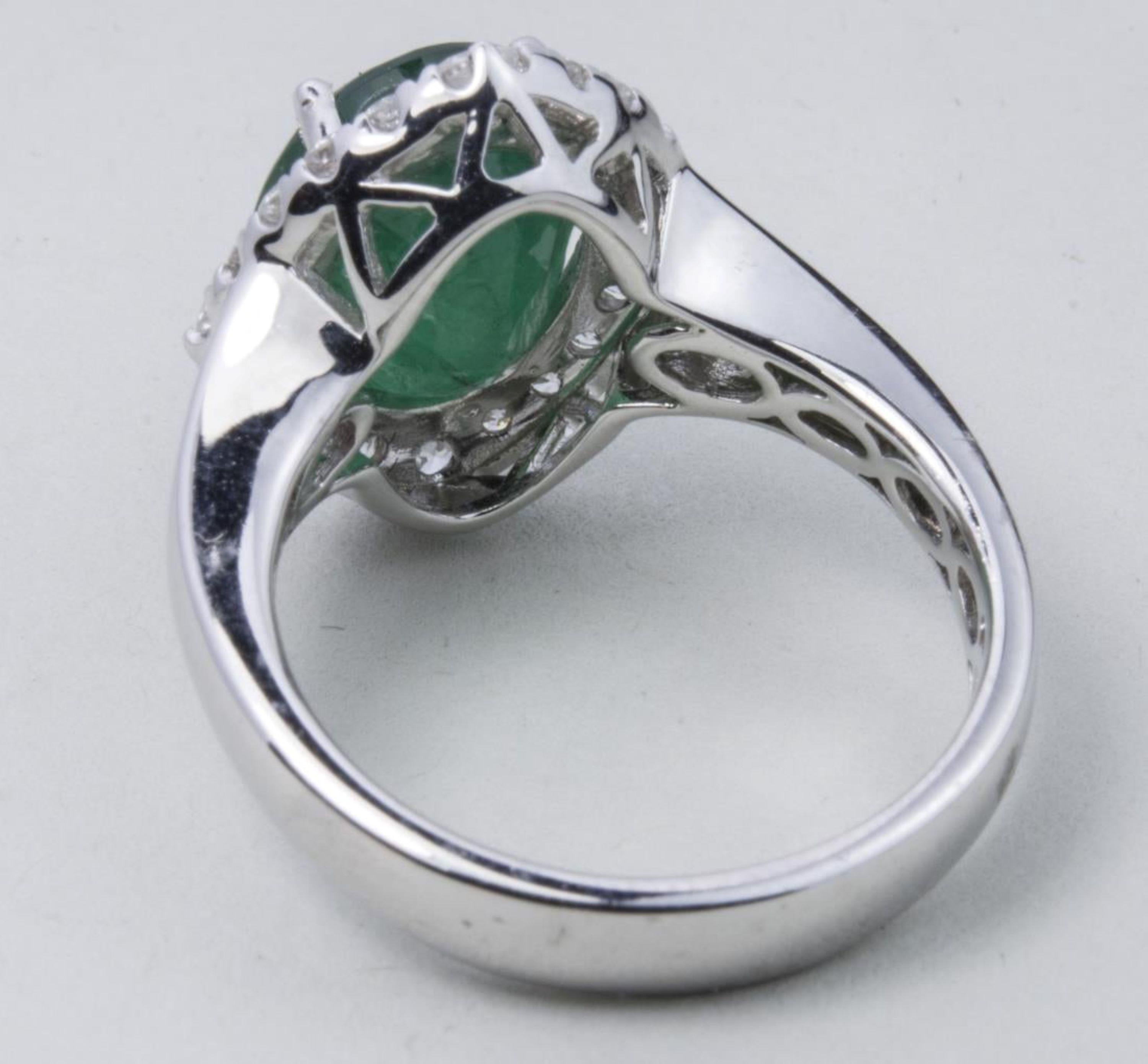 18k white gold ring, with a central oval faceted emerald weighing 3.54 carats surrounded by round diamonds weighing a total of .63 carats.  Size 6 3/4