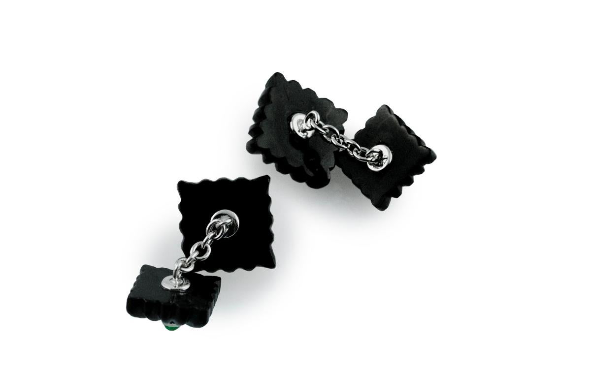This striking pair of cufflinks features squared front faces and toggles. Both elements are enriched with the classic “fesonato” texture and made of onyx, whose striking black shade is accented with the cabochon emerald that graces the center of
