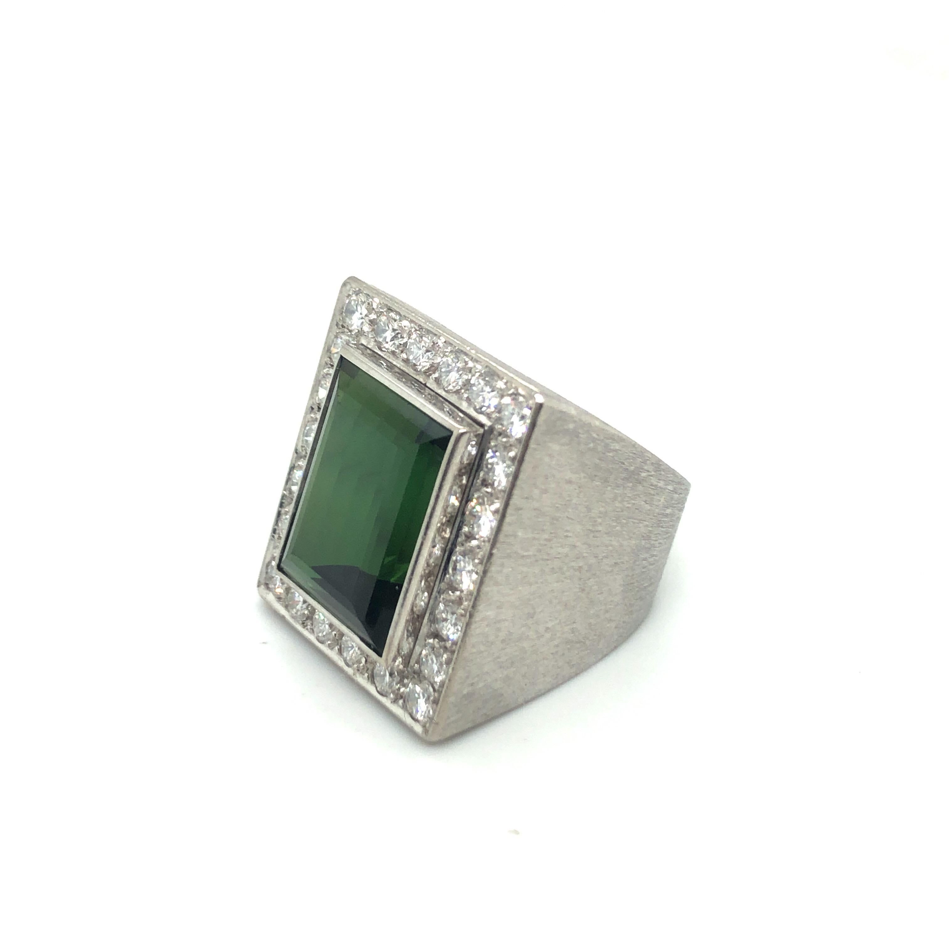 Audace e scintillante anello cocktail in oro bianco 18 carati con tormalina verde e diamanti.
Impressionante anello da cocktail con una tormalina verde rettangolare di circa 13 carati incorniciata da un entourage di 22 diamanti taglio brillante per
