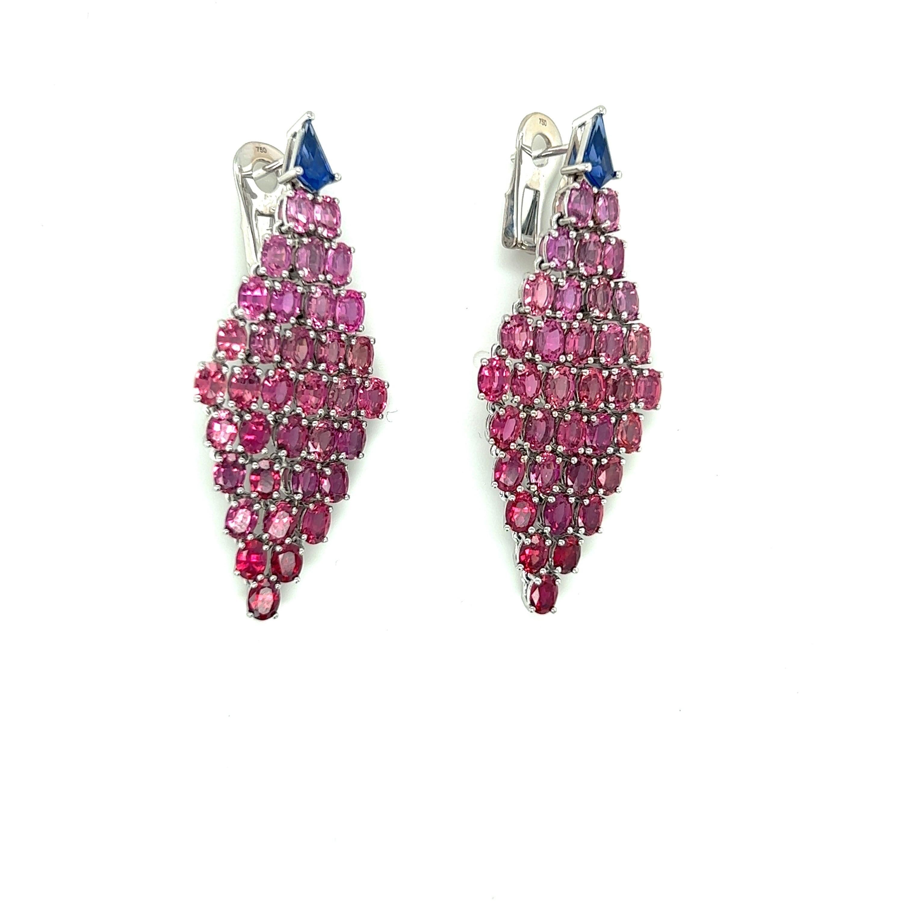 These magnificent earrings are a true show stopper.
The 18 karat white gold earrings are set with 14.20 carats of varying shades, from pink to red, of ombre' rubies.The tops are set with 0.98 carats of blue sapphires.
The earrings are pierced and