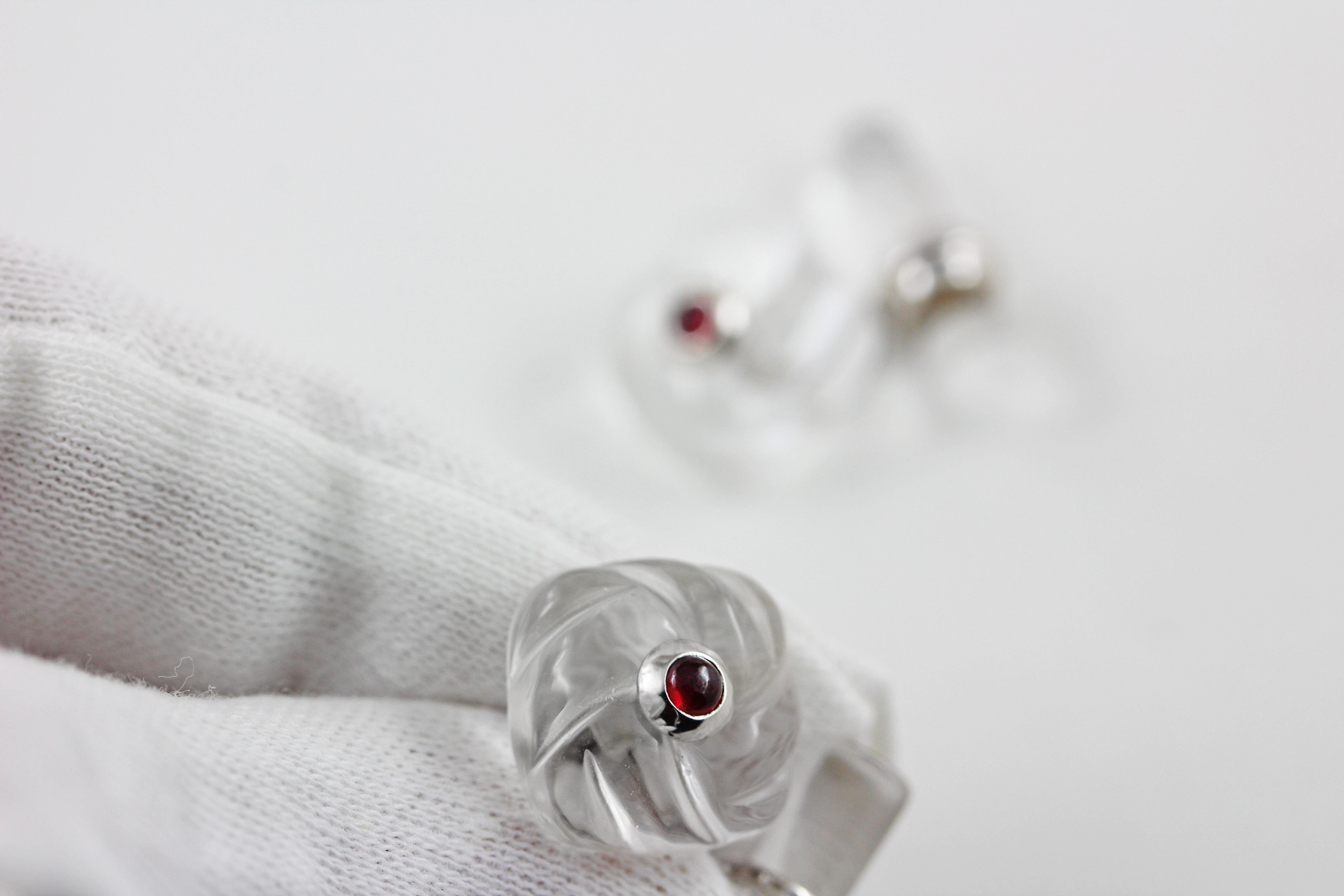 These classic cufflinks are made of rock crystal and feature a front face shaped as a square with a striking texture that mimics an interwoven fabric. 
The squares are adorned in the center with cabochon ruby. 
The toggle is a simple cylinder that