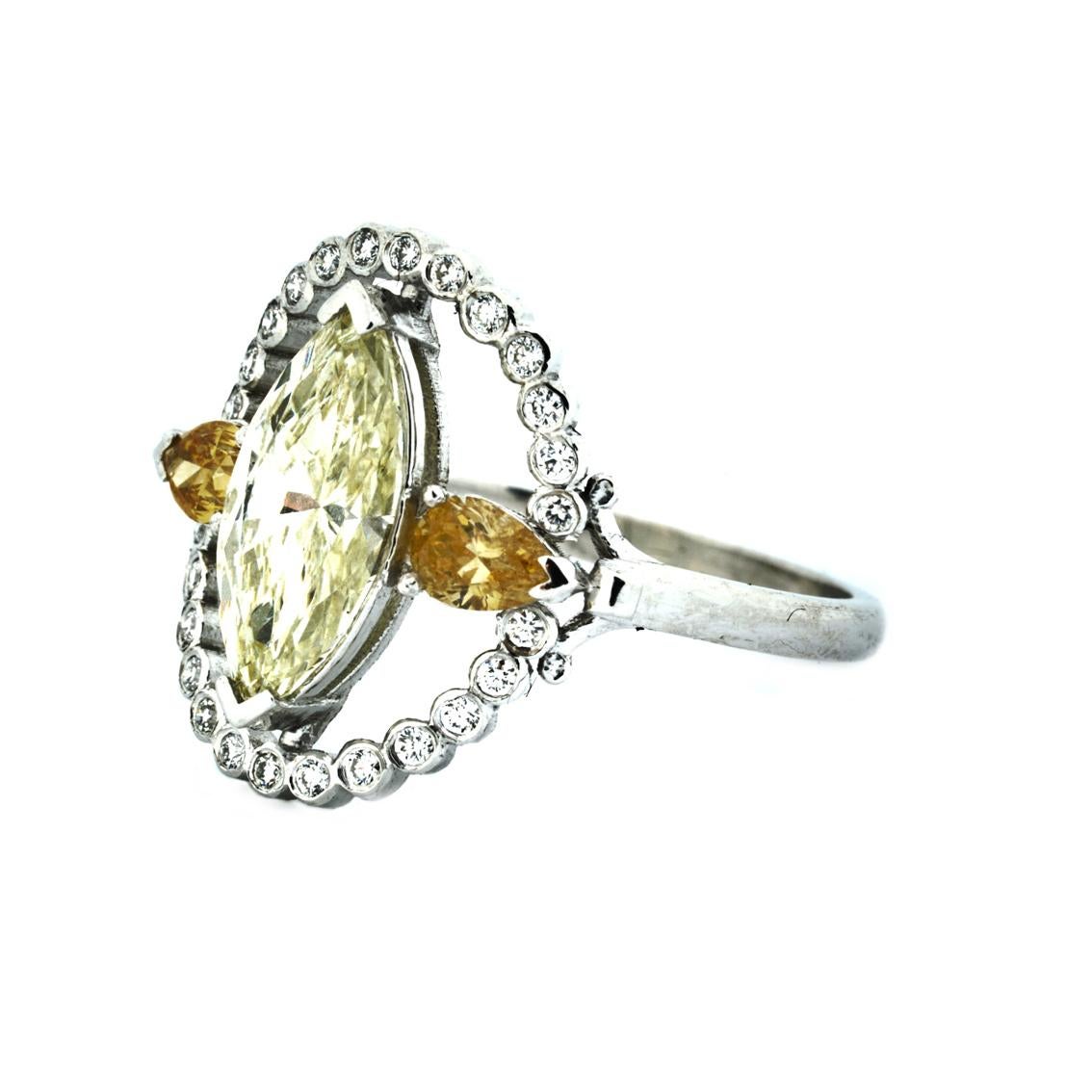 Handcrafted in 18kt white gold, this ring features a central marquise cut diamond, flanked by 2 pear cut diamonds within a halo of 26 round brilliant cut diamonds.

The central marquise diamond in a shade of beautiful pale green/yellow is SI in