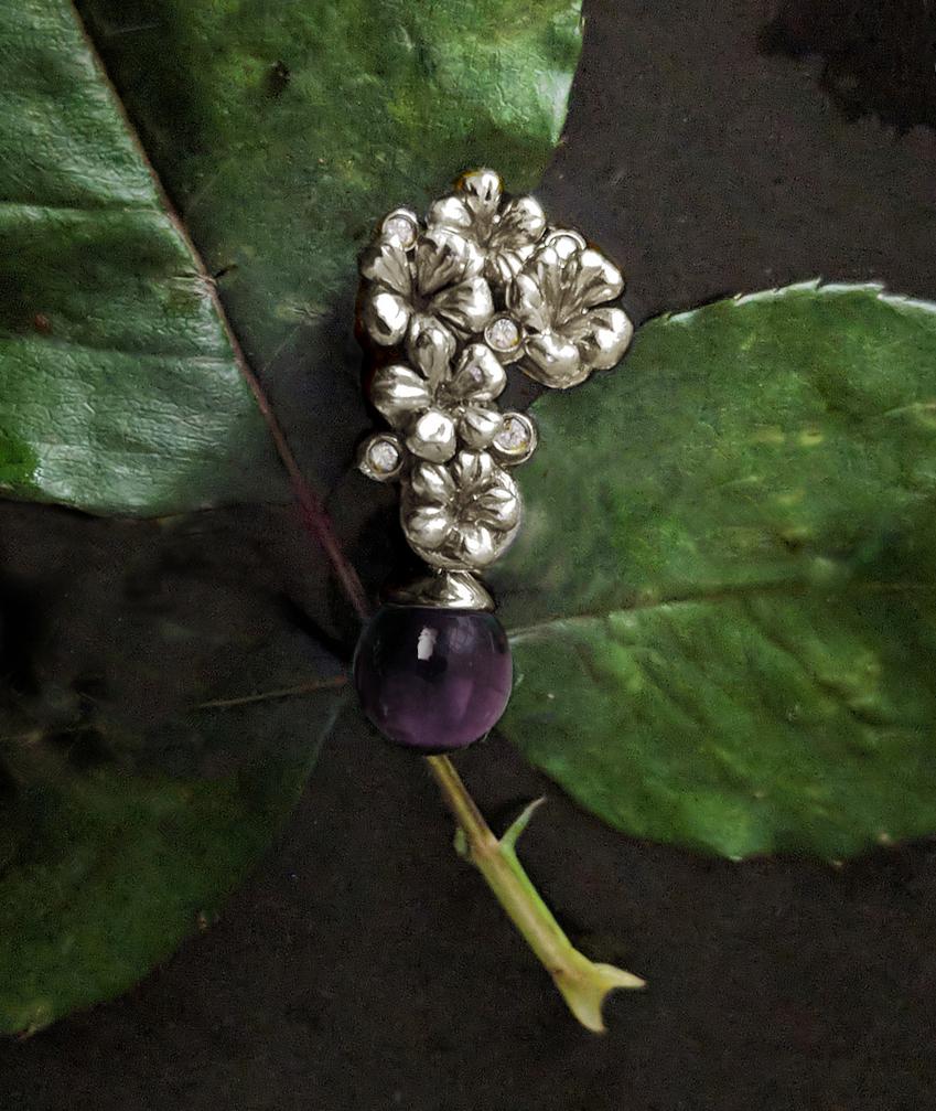 The 14 karat white gold Plum Blossom modern style brooch is encrusted with five round diamonds and a cabochon amethyst drop, and has been featured in a review by Vogue UA. We use only top-quality natural diamonds of VS clarity and F-G color, sourced
