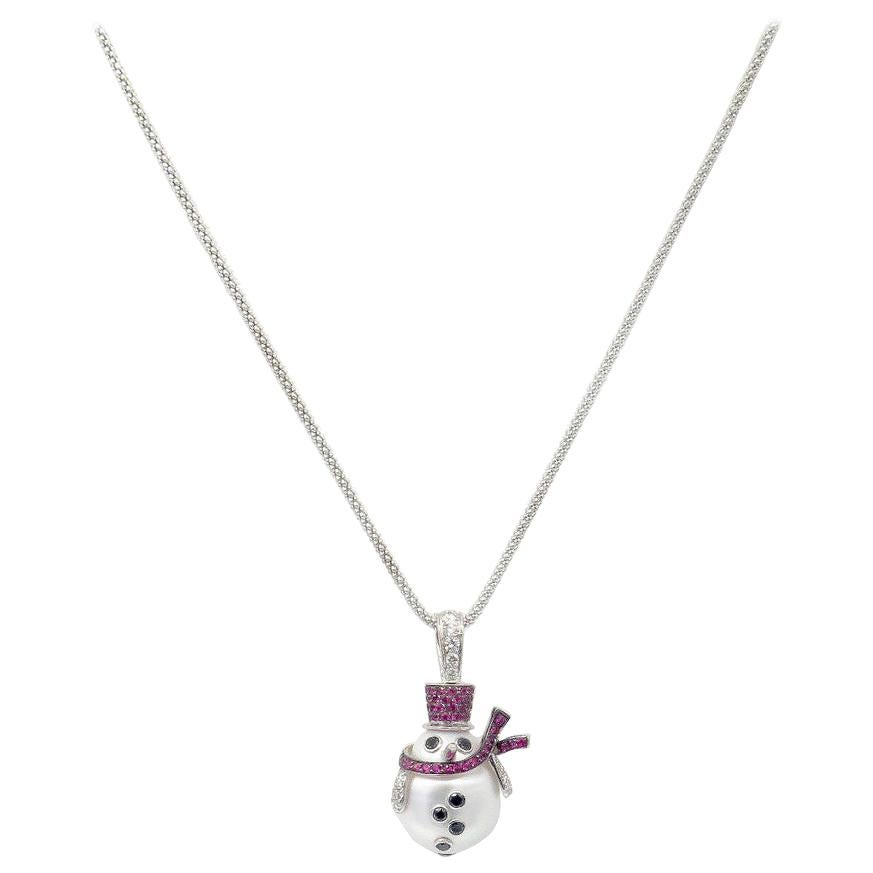 This fanciful mother of pearl snowman is dressed up in style with a shimmering ruby top hat and flowing ruby scarf, white diamond mittens and black diamond buttons and eyes. Set in 18k white gold, this shiny little snowman is dangling from a white