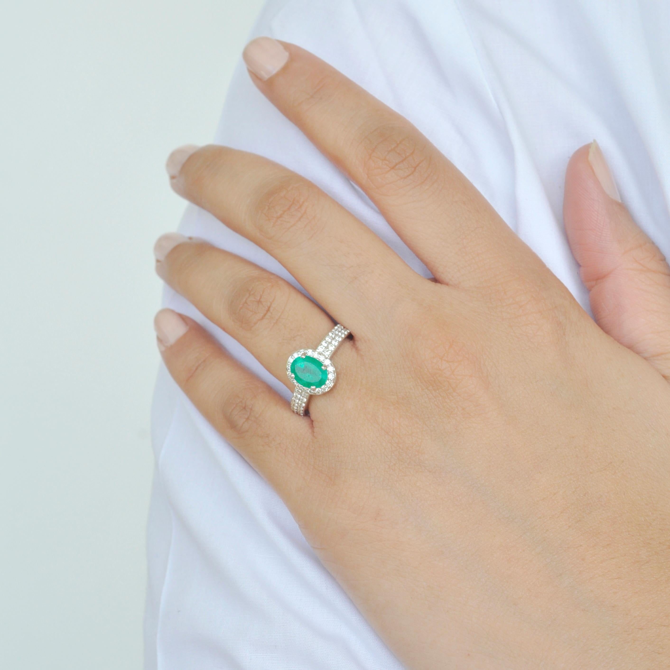 18 karat white gold oval 8.4x6.4 mm colombian emerald diamond contemporary ring.
This emerald diamond ring personifies simplicity and elegance. Encircling the original colombian emerald and the sides of the shank are brilliant cut round diamonds.