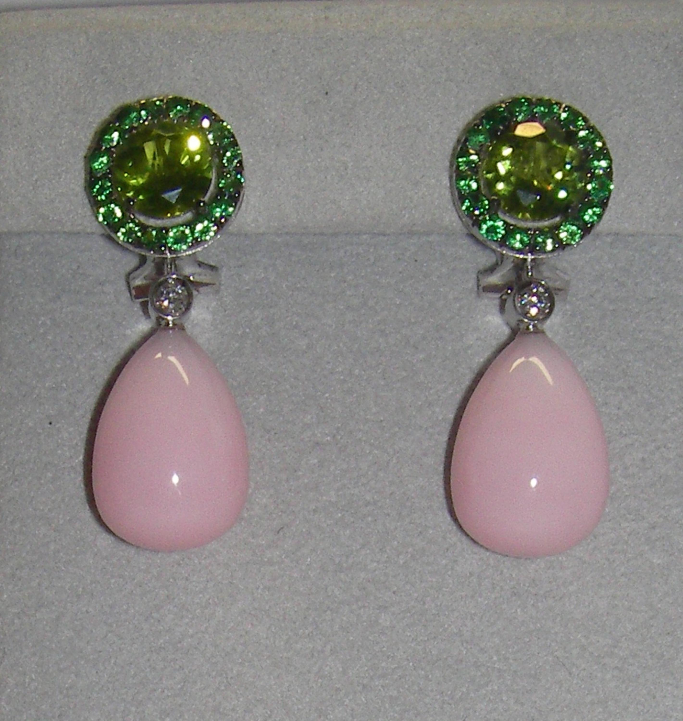 A beautiful set of dangle earrings with a round cut peridot centerpiece at the base, and a tsavorite halo. The base is followed by a single diamond stone and a pear-shape cabochon rose opal. 