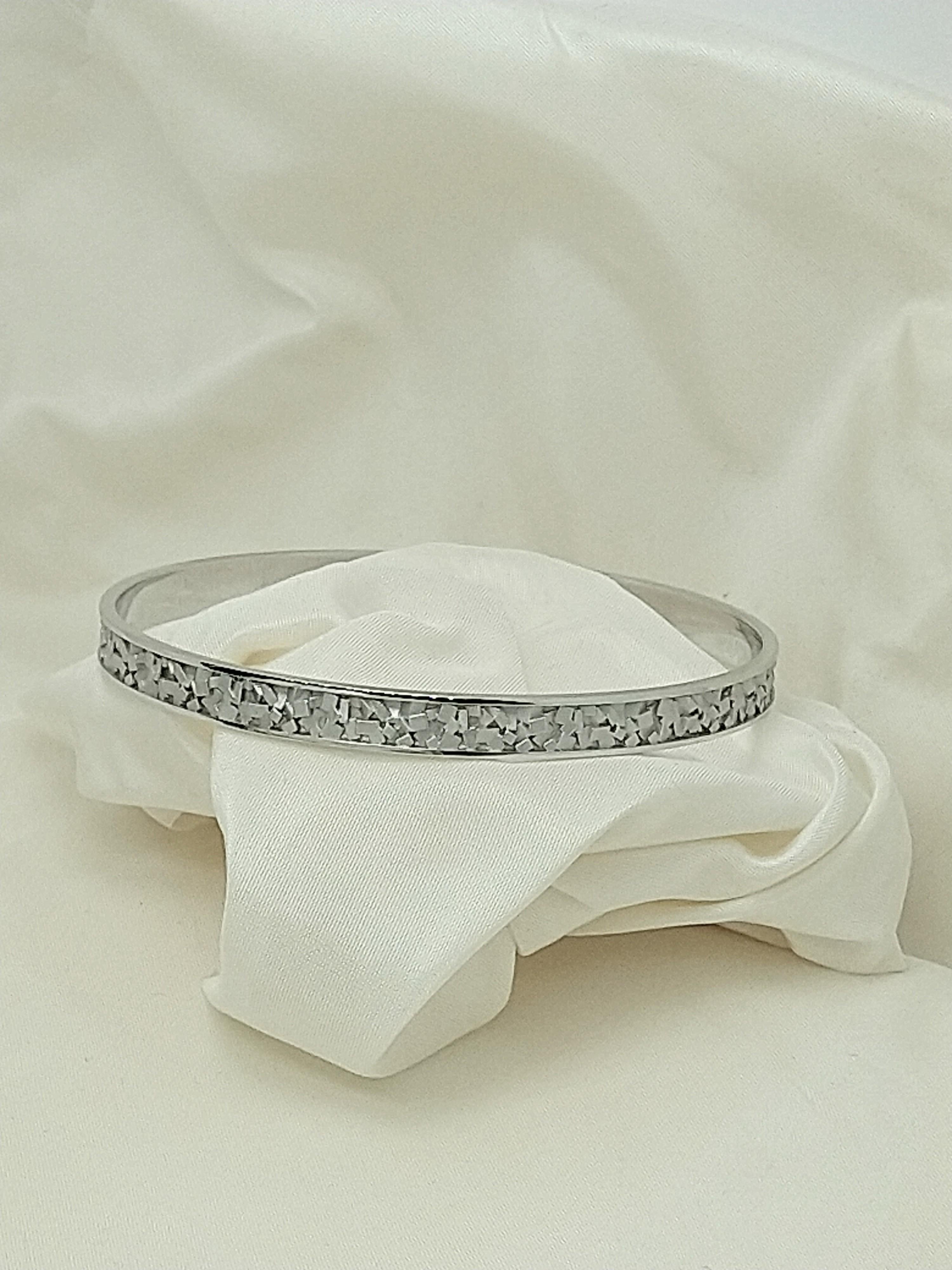 Bracelet jonc rectangulaire en or blanc 18 carats, le designer de Tiffany, Thomas Kurilla, a utilisé de petits rectangles pour concevoir ce simple bracelet jonc. Ce bracelet possède :  Des rectangles mats éparpillés sur le pour créer une texture