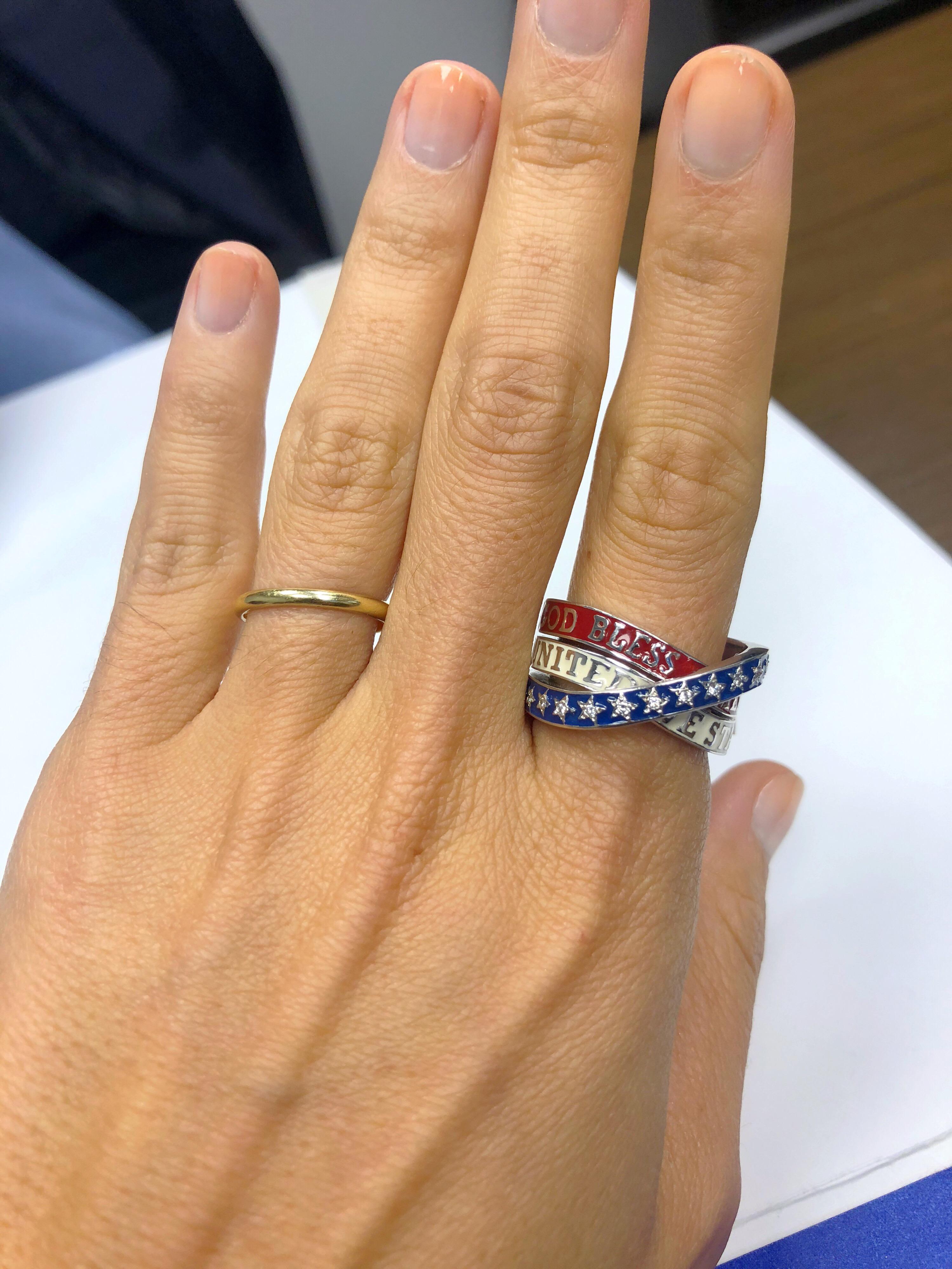 The all American Tribute ring , created exclusively for Cellini. This 3 band crossover ring is crafted  in 18 karat gold with red, white, and blue enamel. God Bless America, United We Stand is applied in white gold letters on the red and white