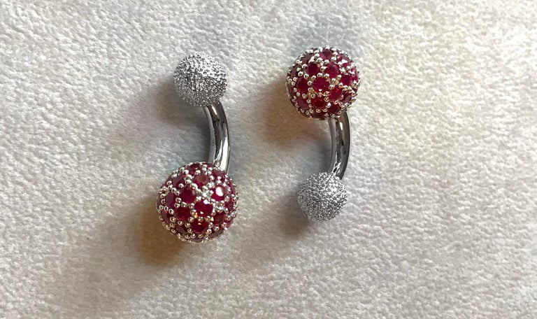 These elegant cufflinks are made entirely of 18k white gold. The large spherical front face is completely covered in rubies , while the toggle is shaped as a smaller sphere with a multi-faceted texture. A curved post with a polished, smooth surface