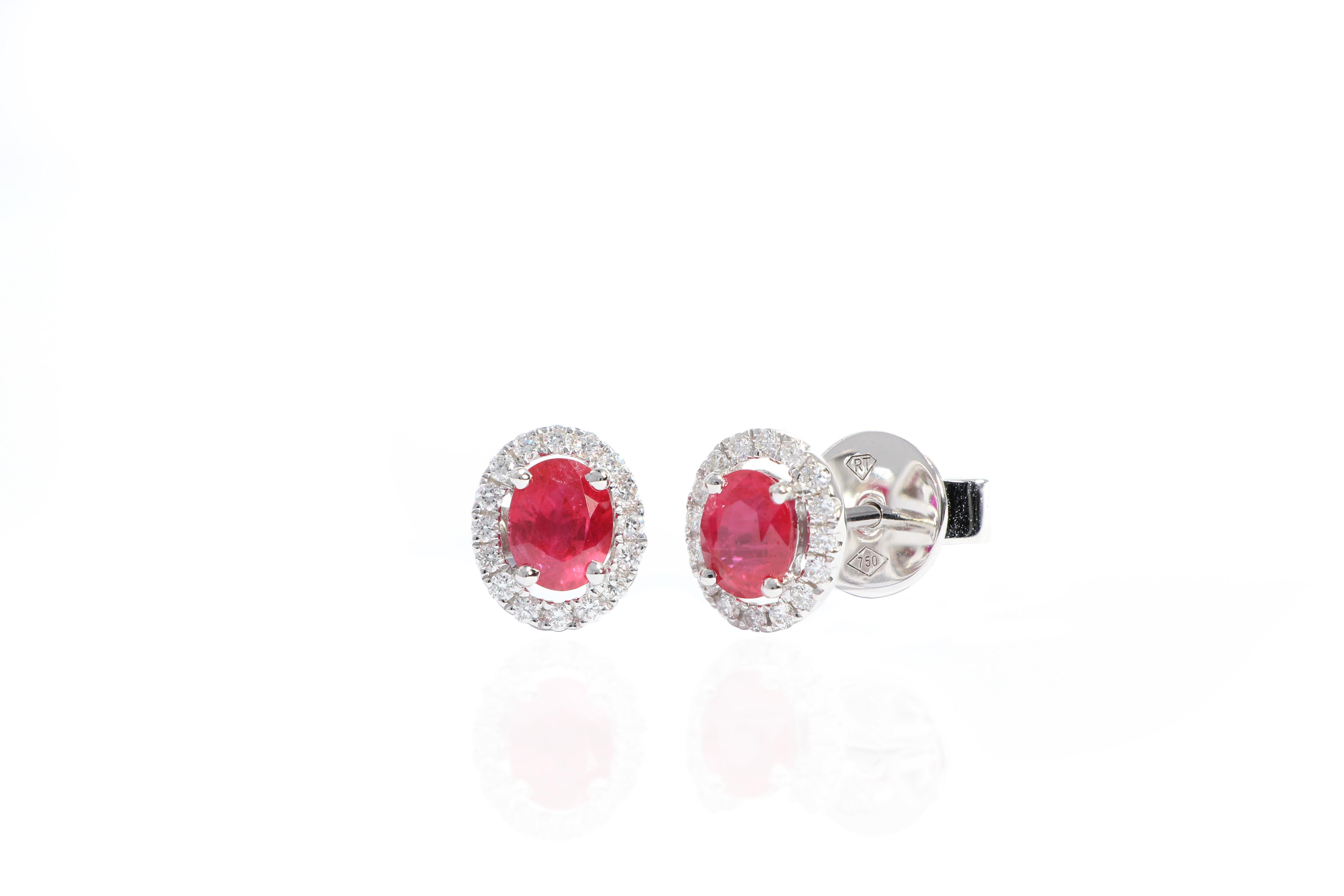 A beautiful pair of earrings,  each side centring on an oval ruby with bright red colour, altogether weighing approximately 0.87 carats, framed by brilliant-cut diamonds altogether weighing approximately 0.17 carats, mounted in 18 karat white