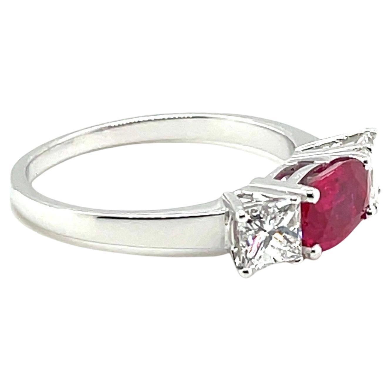Elegant 18 karat white gold ruby and diamond trilogy ring. 

Delightful ring, centering upon 1 oval pinkish-red ruby of circa 1.10 carats, flanked by 2 princess-cut diamonds totalling circa 0.95 carats.  

This beautiful and timeless ring has