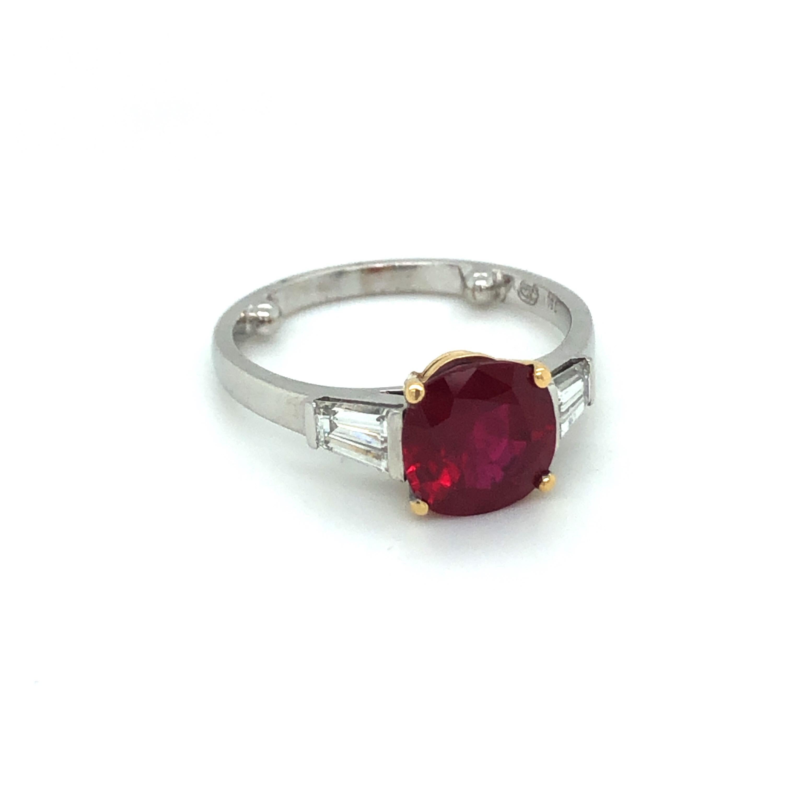 Classic 18 karat white gold ruby three stone ring by renowned Swiss jeweler Gubelin.
This beautiful ring is set with a fiery cushion-shaped 2.9 carats Thai ruby of impeccable quality flanked by two tapered diamonds totalling 0.64 carats. The mount