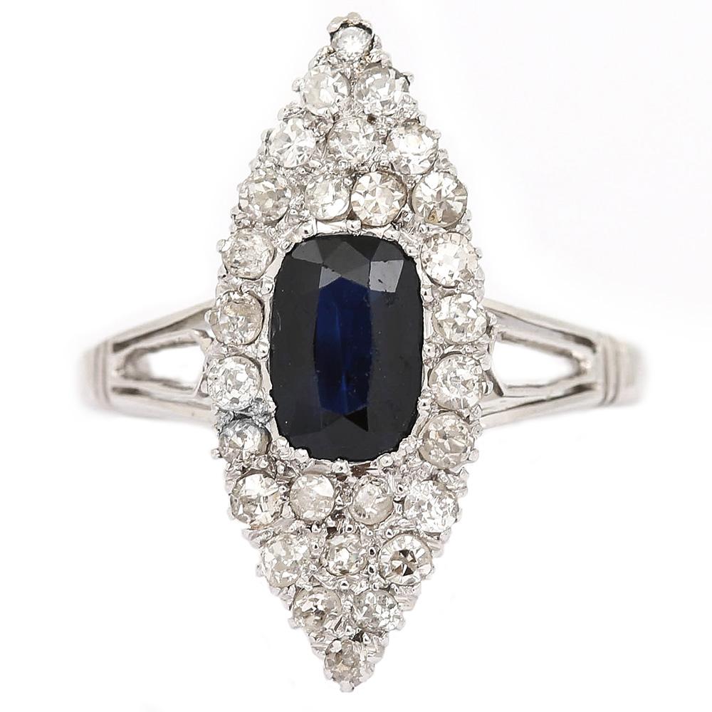 A striking vintage 18 karat white gold sapphire and diamond marquise diamond ring that has been made using Old Mine cut diamonds. Total estimated diamond weight 0.70ct with a 1.30ct oval mixed cut deep blue sapphire. The pavé set stones are set in