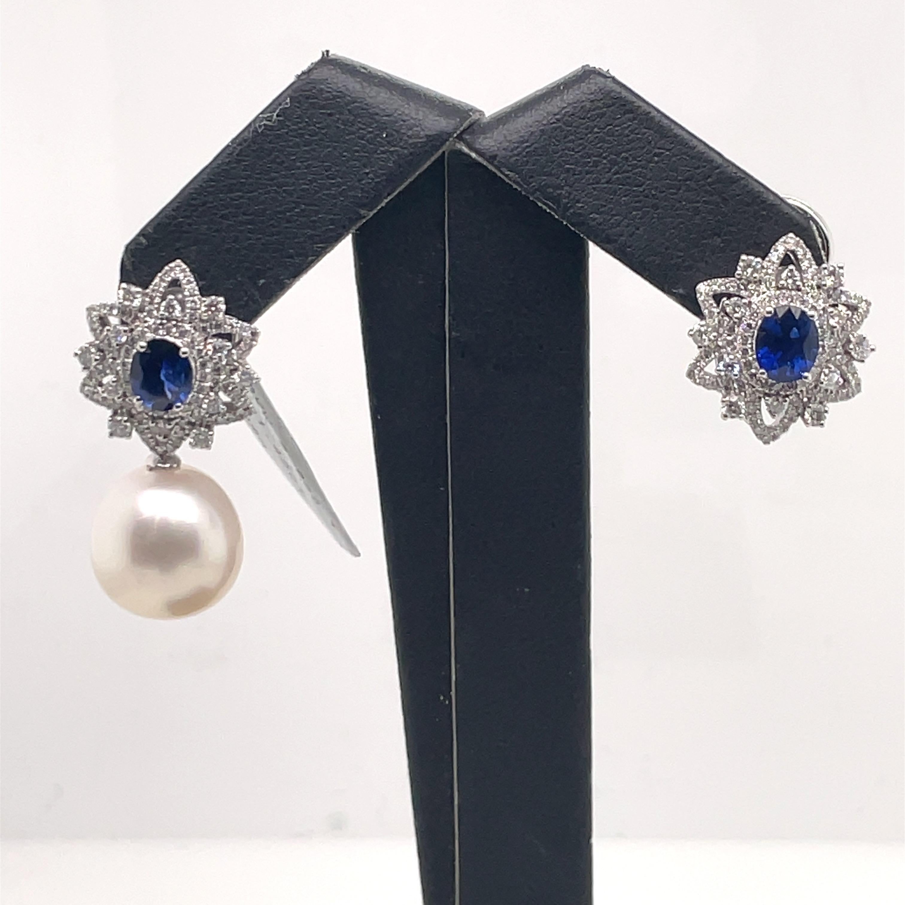 18 Karat white gold earrings featuring two blue Sapphires weighing 1.45 carats flanked with round brilliants in a floral motif weighing 1 carats and two white South Sea Pearls measuring 12-13 MM.

Earrings can be worn as a stud or drop earring.