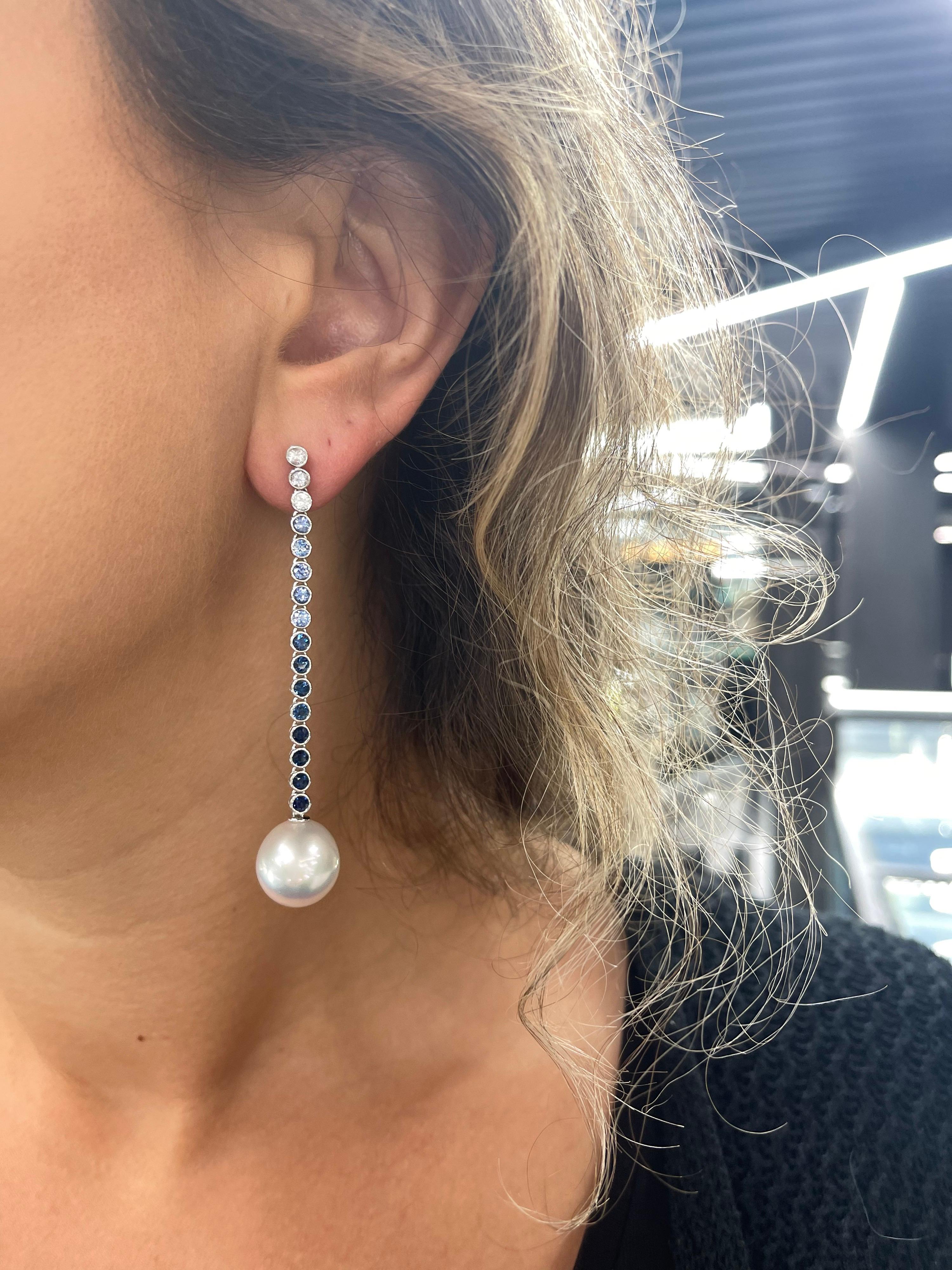 18 Karat white gold drop earrings featuring an ombree motif of white sapphires to blue sapphires and two white South Sea Pearls measuring 13-14 mm.
6 White Sapphires weighing 0.57 carats and 26 blue sapphires weighing 2.42 carats.