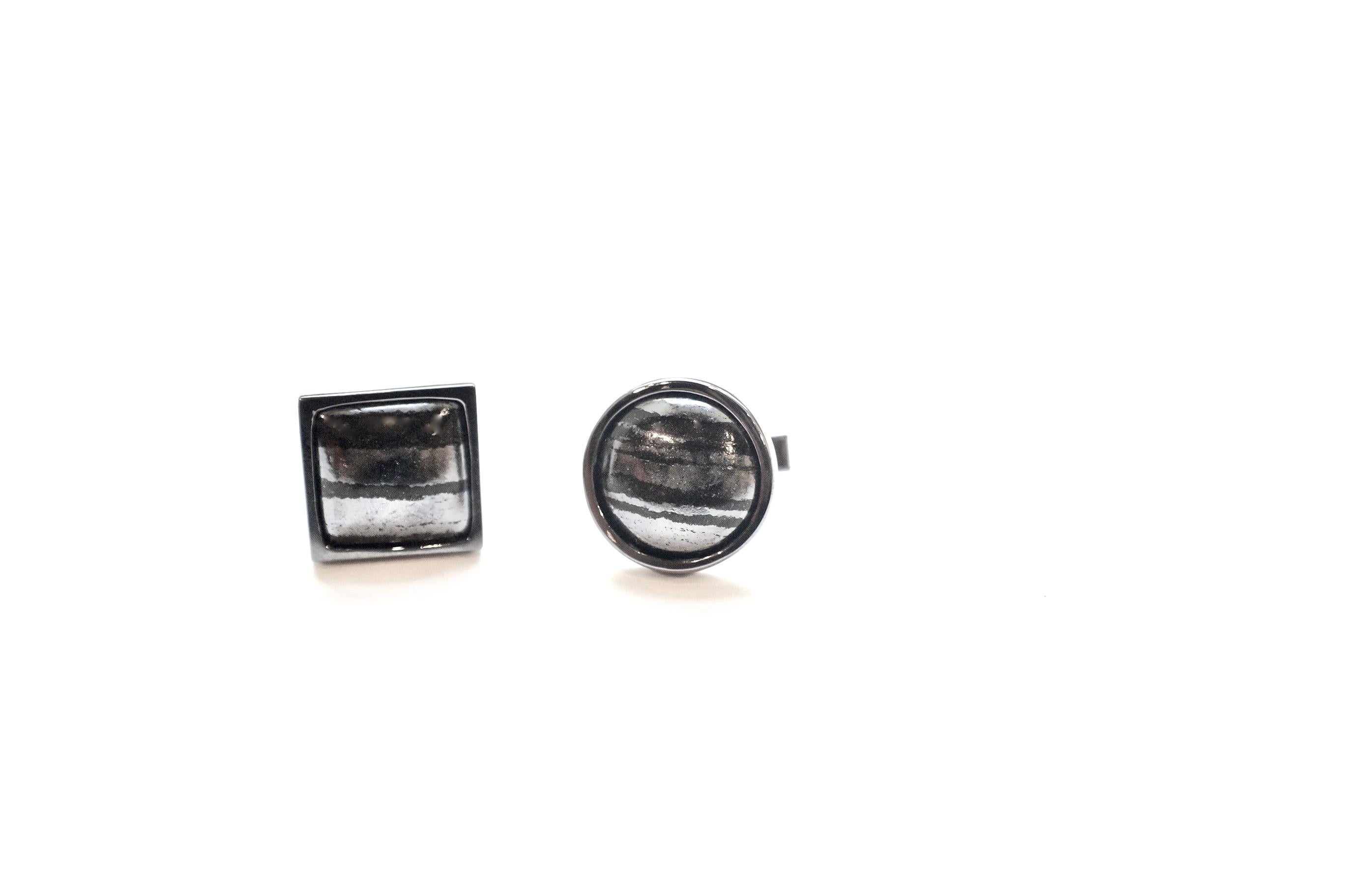 Swedish Slag Cufflinks
A pair of eighteen-karat blackened white gold cufflinks, each set with a Swedish slag cabochon, one round, and the other square. 
Swedish Slag Total Weight – 43.54 cts.
This piece, in its entirety, has been created and