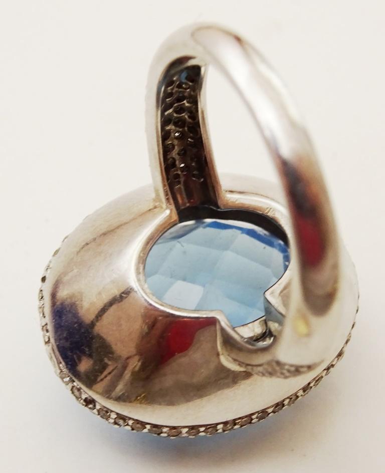 This Ring is from the 1960's. 
It is made in fully hallmarked 18 karat White Gold weighing some 25 carats
The Central stone is a 15 x 20 mm oval checker cut Swiss Blue Topaz.
Fringing the stone  and on the flanks of the shank there are set some 340