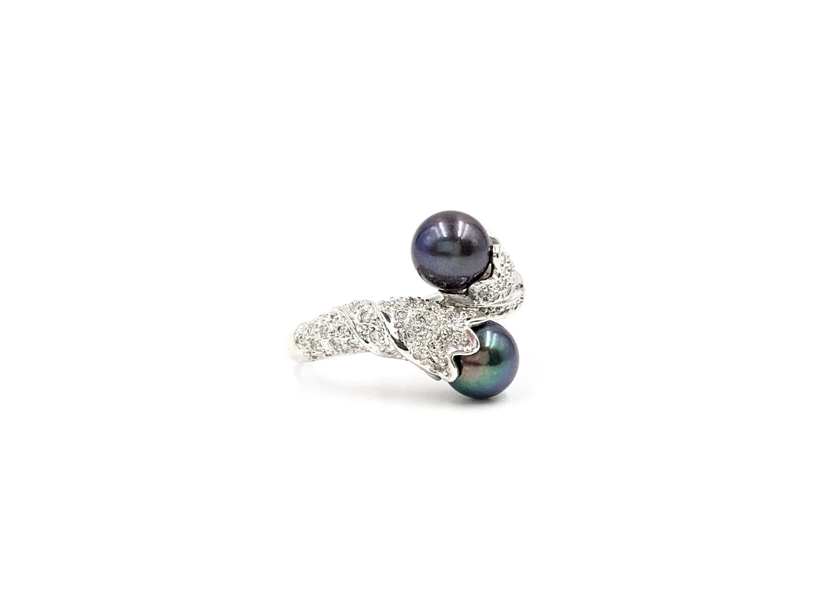 A very well made 18 karat white gold 'Toi et Moi' bypass style ring featuring two 7mm round well saturated Tahitian pearls and approximately .50 ct round brilliant diamonds, arranged in a beautiful twist design. Diamond quality is approximately G-H