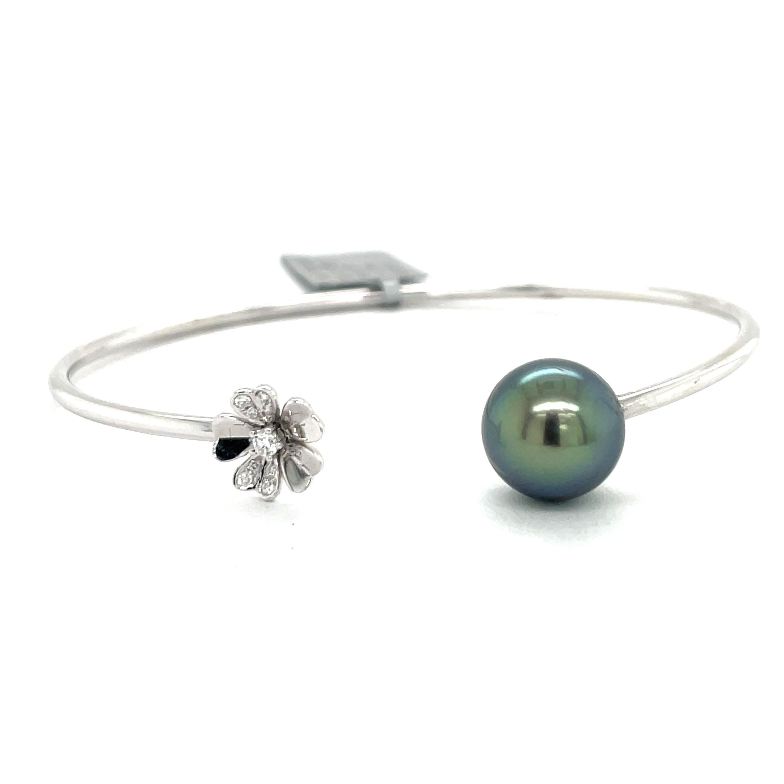 18 Karat White Gold open cuff bangle featuring one Tahitian Pearl measuring 11-12 MM and one floral motif containing 9 diamonds weighing 0.07 Carats.
