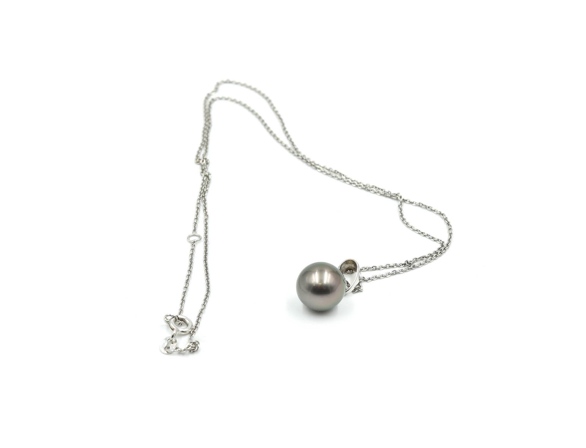 This necklace is crafted in 18k white gold featuring a simple cap and bail pendant holding an 10.7mm Tahitian pearl. The pendant is suspended on a simple link 18” inch long chain. This necklace weighs 1.2 grams. 

