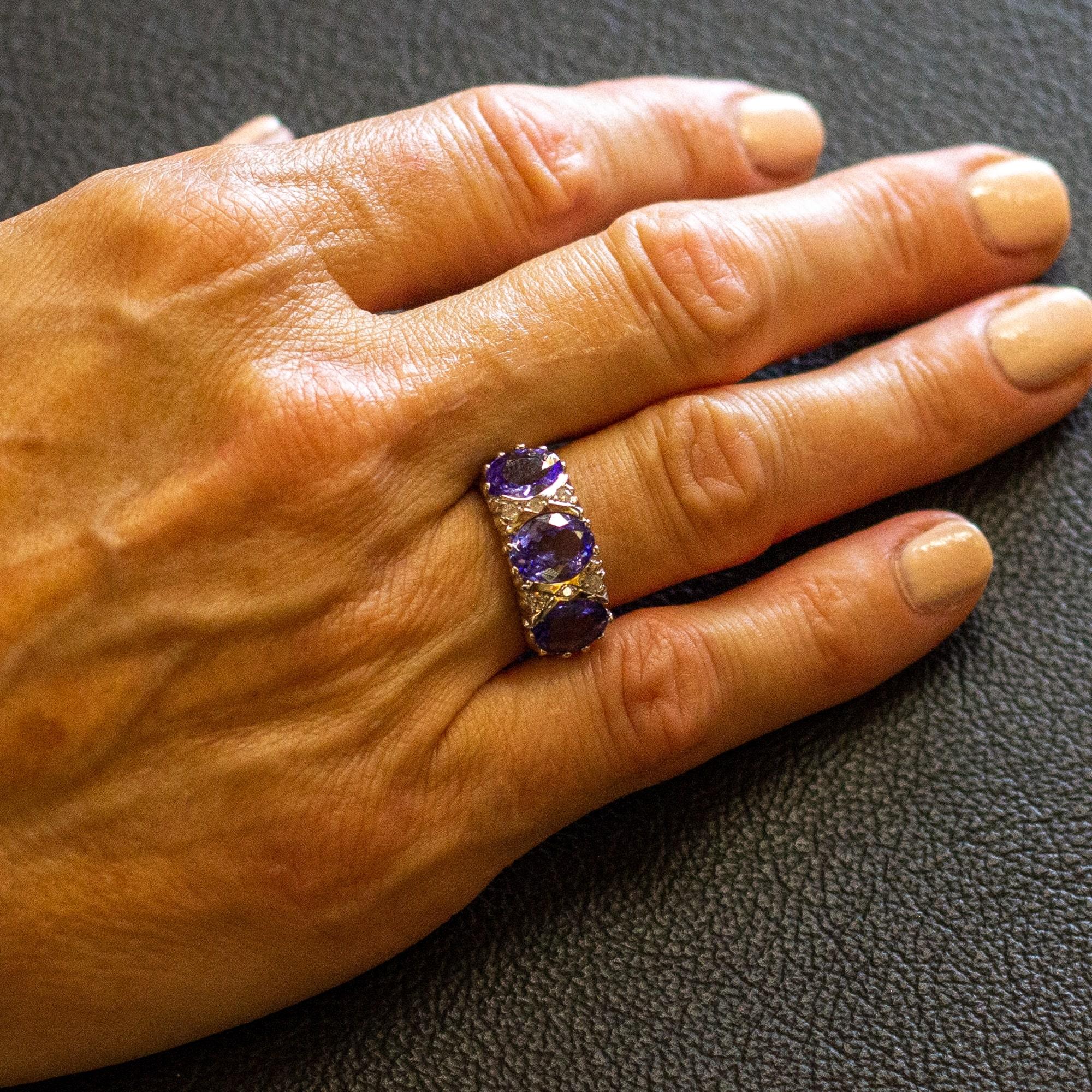 An 18 karat white gold, tanzanite and diamond ring. The dress ring features three oval cut tanzanites weighing 3.30 carats combined, interspersed with six round brilliant cut diamonds. The colour of the tanzanite stones in this particular ring is a