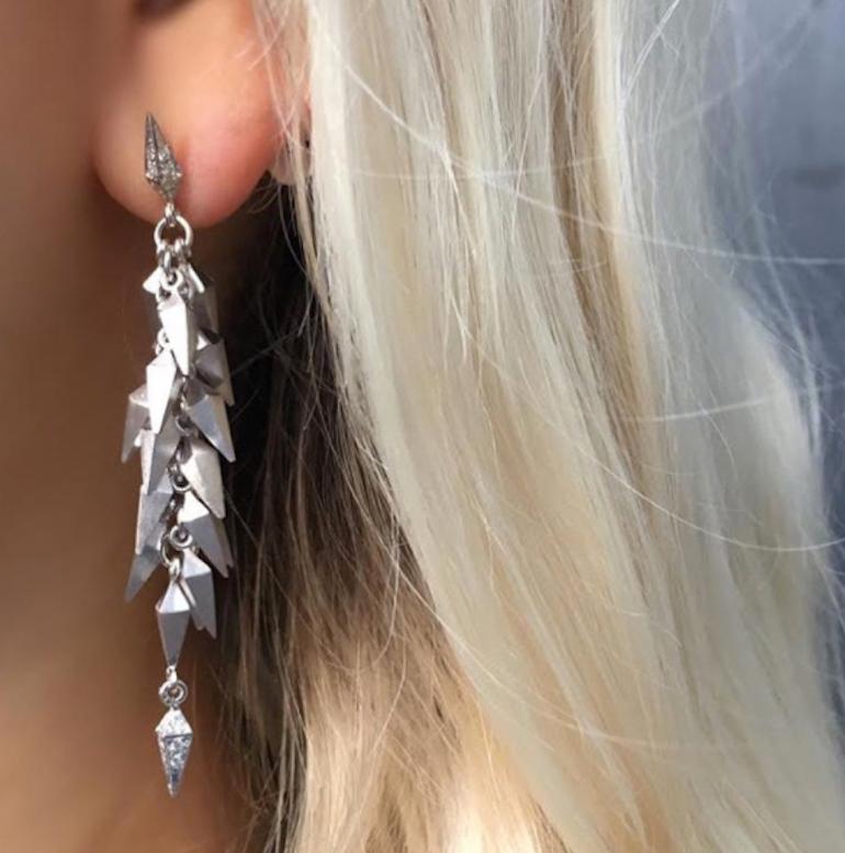 Trickling Stardust Dangle Earrings feature Karma El Khalil's signature pyramid spike motif with white diamond studs and clusters of solid white gold pyramid spikes dangling down and finished at the tips with diamonds
18k White Gold, White