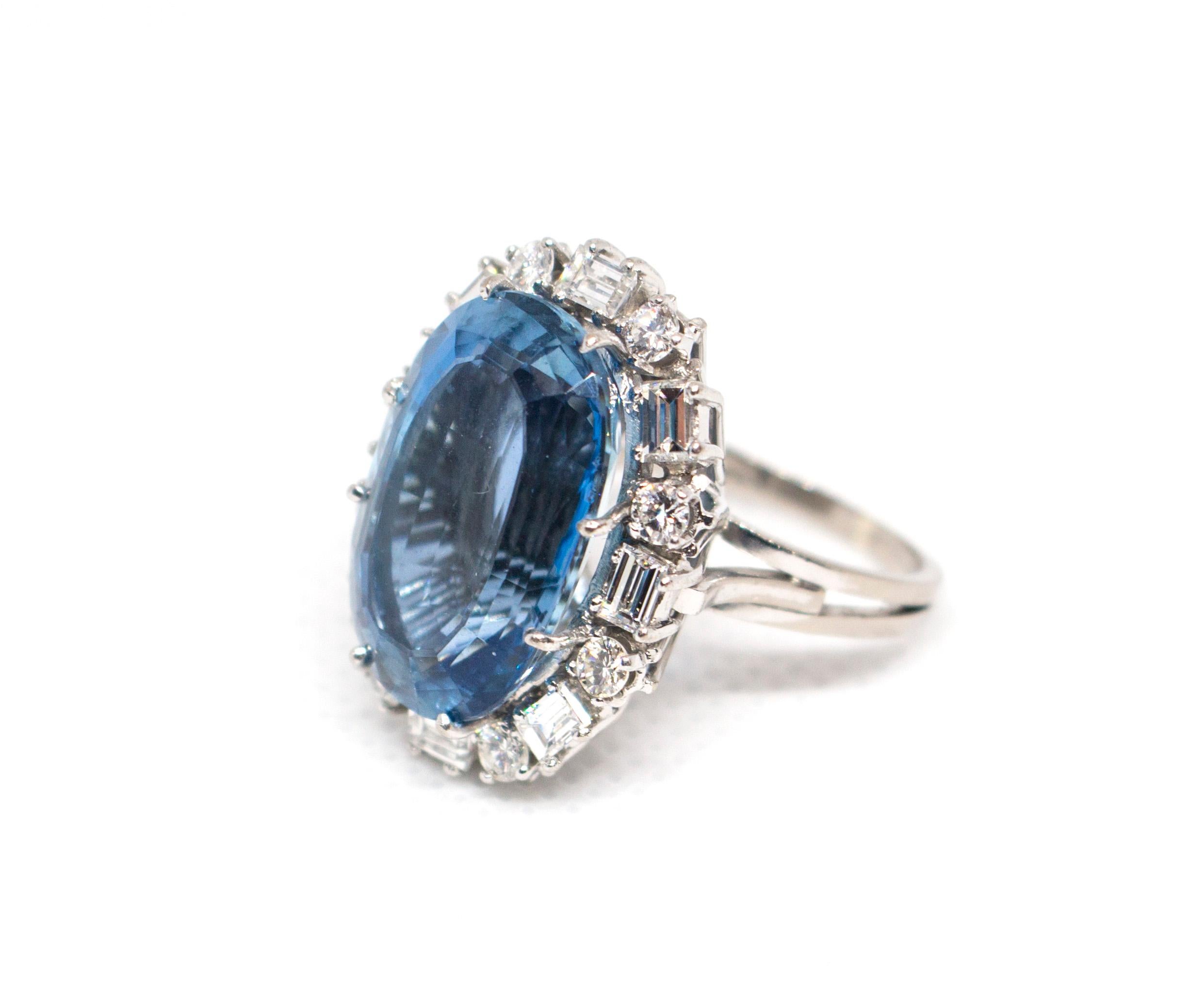 An 18 Karat White Gold, Aquamarine and Diamond Ring, 
containing one oval step cut aquamarine weighing approximately 11.00 carats, eight round brilliant cut diamonds weighing approximately 0.48 carat total, VS1-VS2 clarity, E-F color  and eight