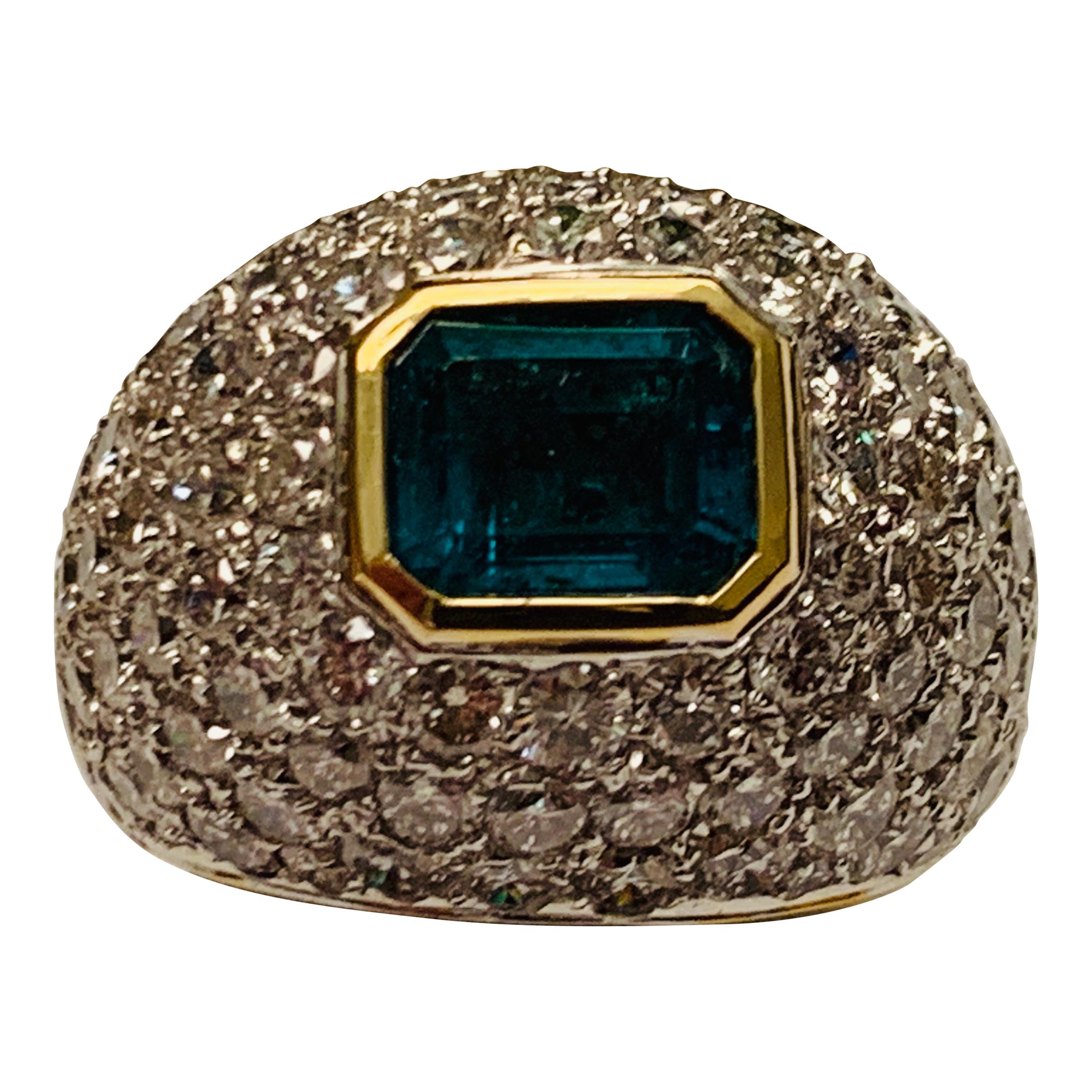 This 18 K white and yellow Gold emerald and diamond dome shaped cocktail ring features a nice bezel set emerald of approximately 2 carats wich is embedded by 100 pavé set diamonds of ca. 3 ct. 
The ring is currently size 55/15 but can be resized