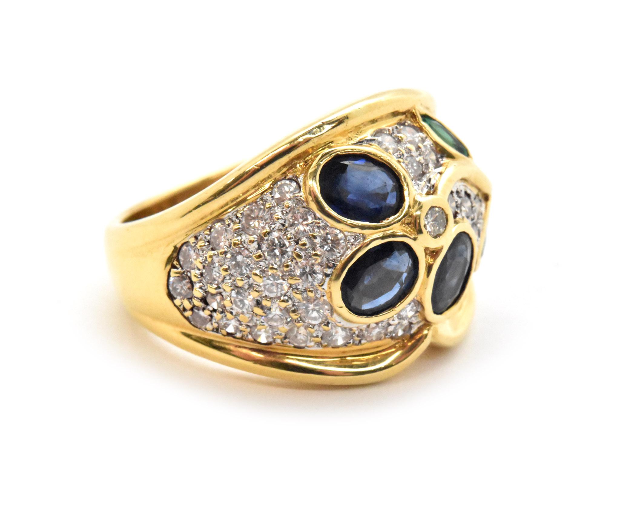 This fashion ring is made in 18k yellow gold and set with gemstones, diamonds on this ring are set across the head of the ring. Diamonds on this ring are round brilliant cut, and reach a total carat weight of 0.98. Sapphires and emeralds are also