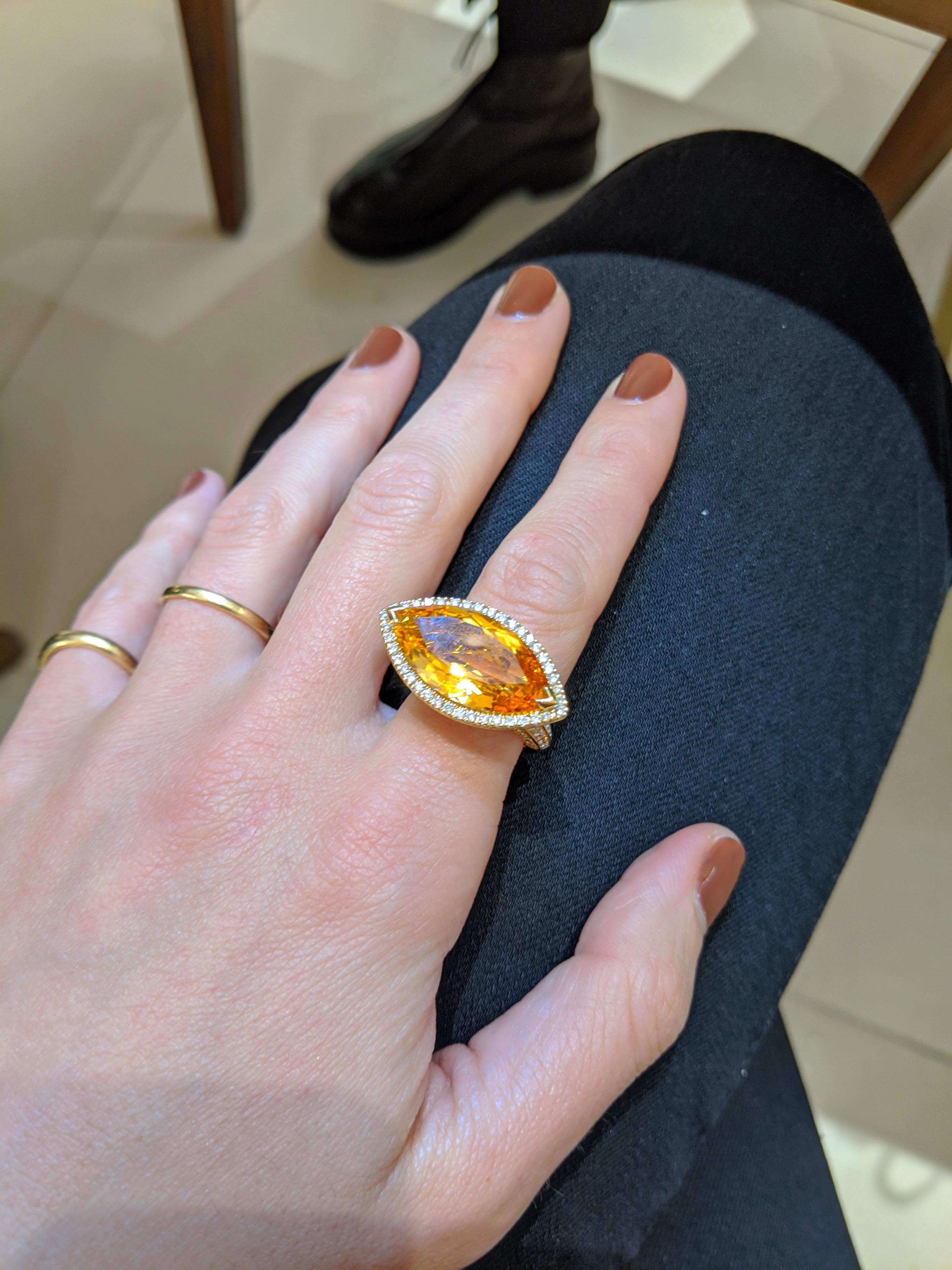 This magnificent statement ring is set with a  large vibrant marquis cut Citrine that has been set east west. The detailed setting has round brilliant diamonds around the Citrine, under the basket,  and 3/4 down the shank. Any direction the hand