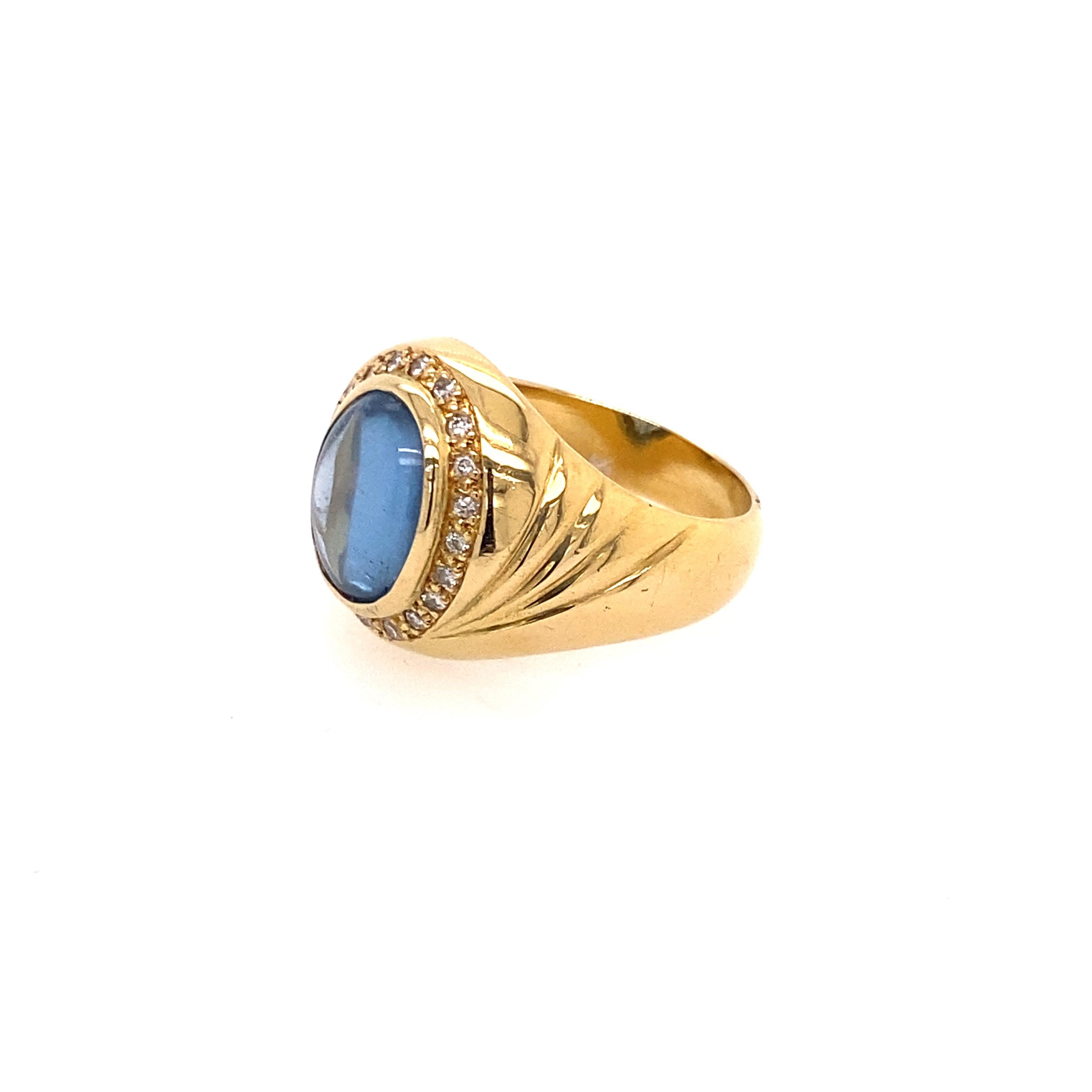 18 Karat Yellow Gold Light Blue Cabochon Sapphire Diamond Ring.

The center stone is a transparent light blue cabochon sapphire secured in a bezel setting. There are twelve round brilliant cut diamonds surrounding the sapphire in grain setting.