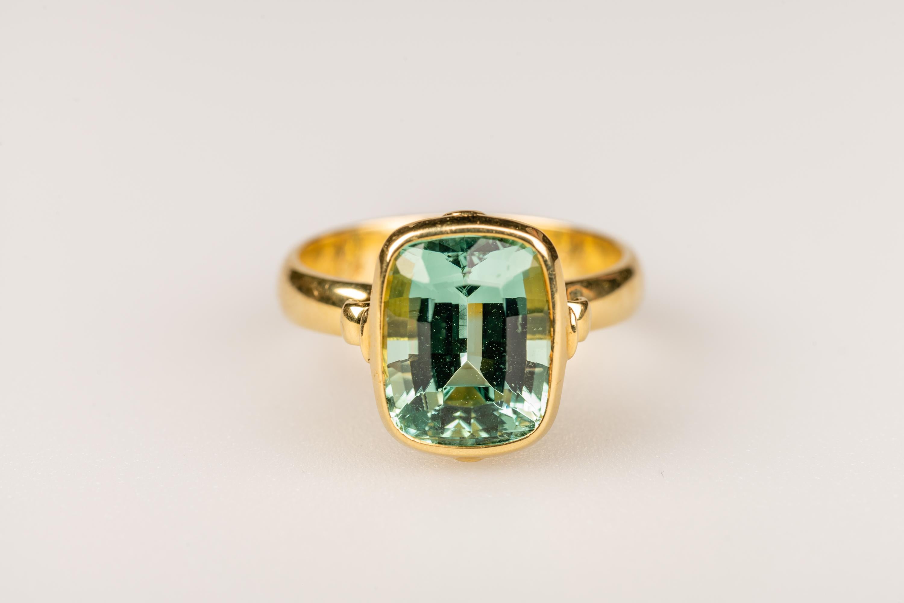 An 18k yellow gold ring bezel set with a custion cut  5.32 carat mint green tourmaline, ring size 7. This ring was designed and made by llyn strong.
