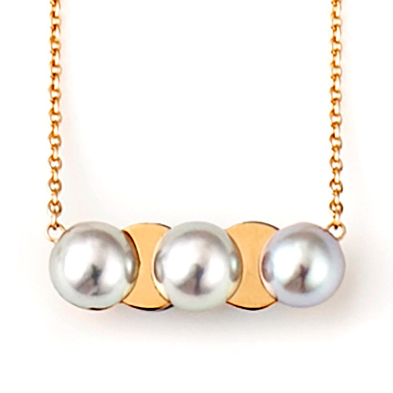 This necklace features a pendant of Akoya pearls of a silver grey hue cut in half and placed on a plate of 18 karat gold, allowing the contrasting materials to show through. It is a reversible design with 3 pearls on one side and 2 on the other. The