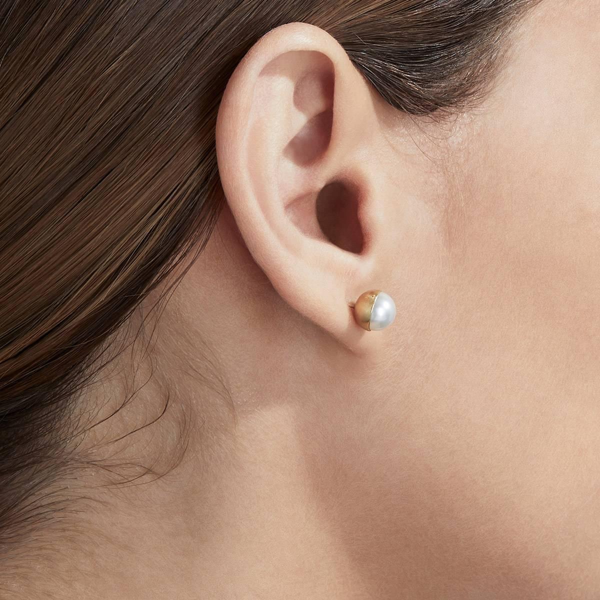 A pearl is encased in a half sphere of gold at a 0 degree angle and placed on a post. Comes with an 18 karat yellow gold earring back. 

Post length: 11mm
Earring back length: 7mm
Akoya pearl: 7mm
This item is sold as a pair
This item is