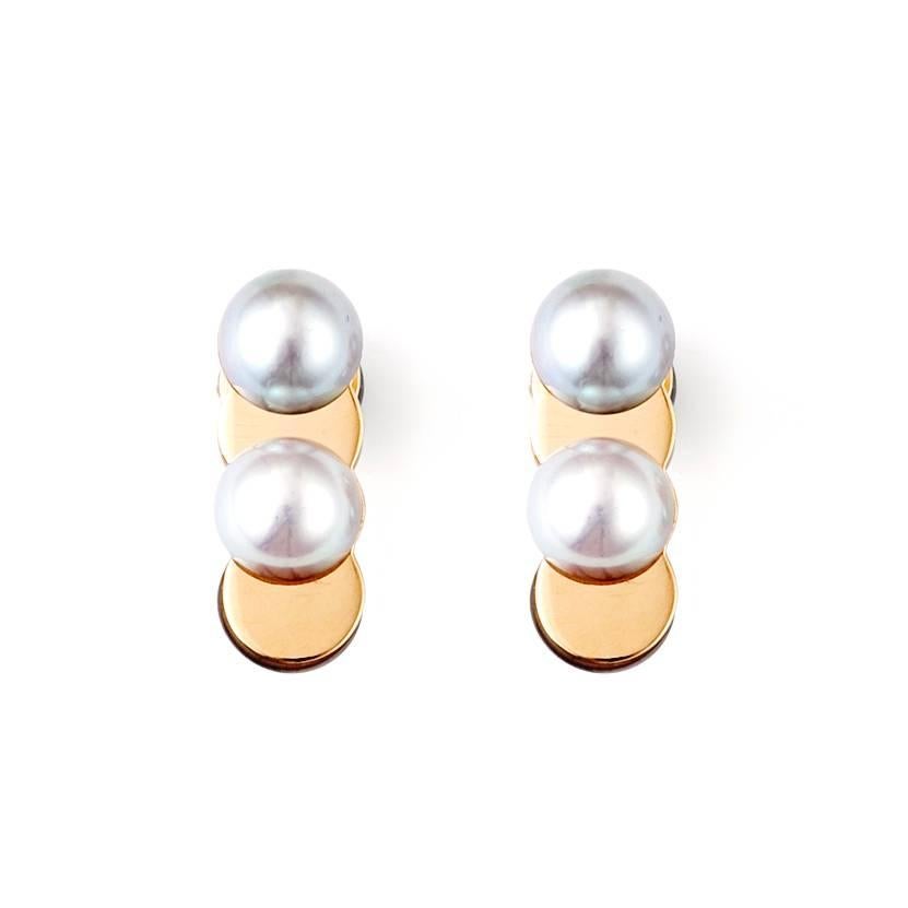 These earrings feature Akoya pearls of a silver grey hue cut in half and placed on a plate of 18 karat gold, allowing the contrasting materials to show through. The earring backs are made of half a pearl and gold and is a reversible