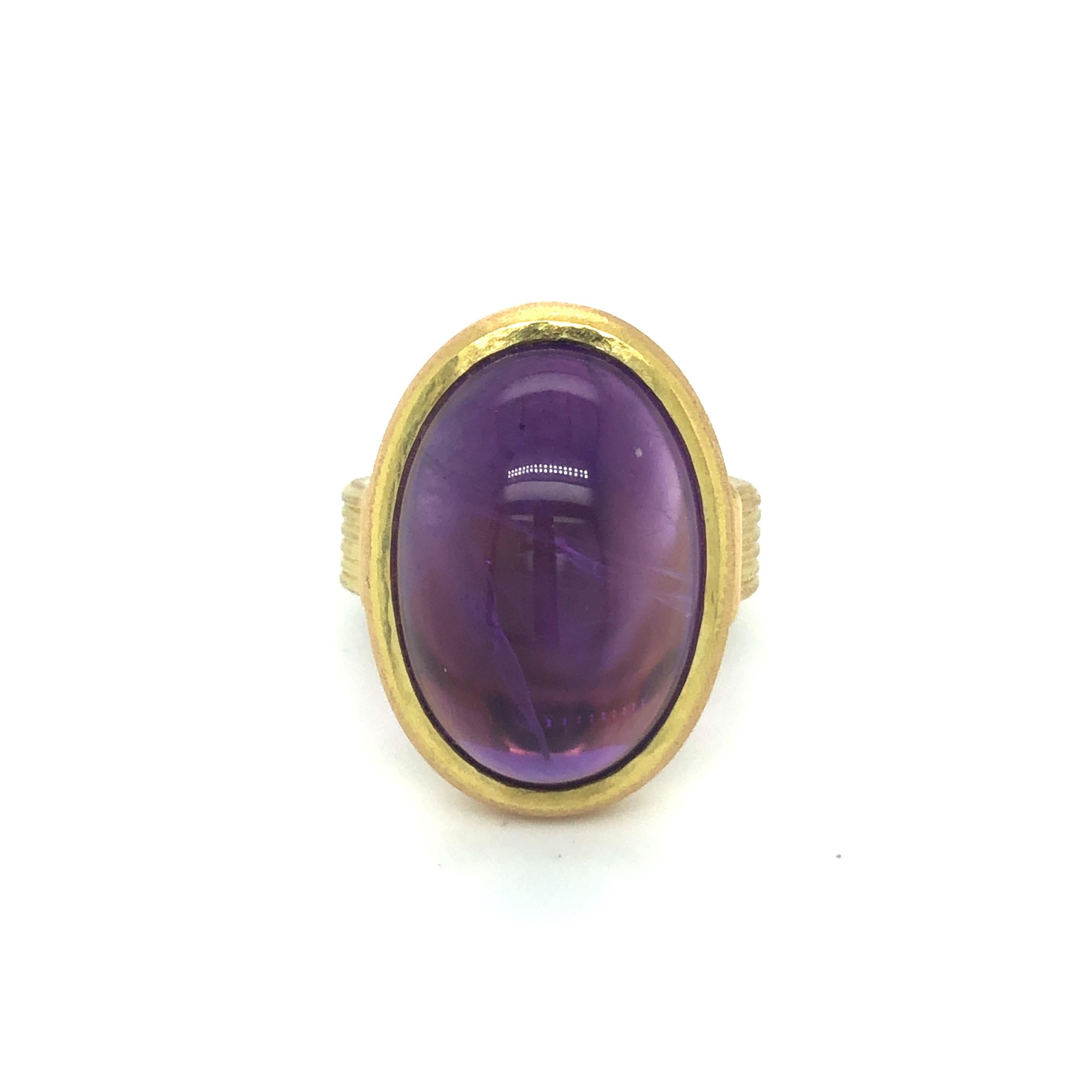 Beautiful 18 karat yellow gold and amethyst cocktail ring.
Crafted in brushed yellow gold and set with an oval amethyst cabochon of circa 18.2 carats, this ring is distinguished by clear lines, perfect proportions and simplicity. The grooved ring