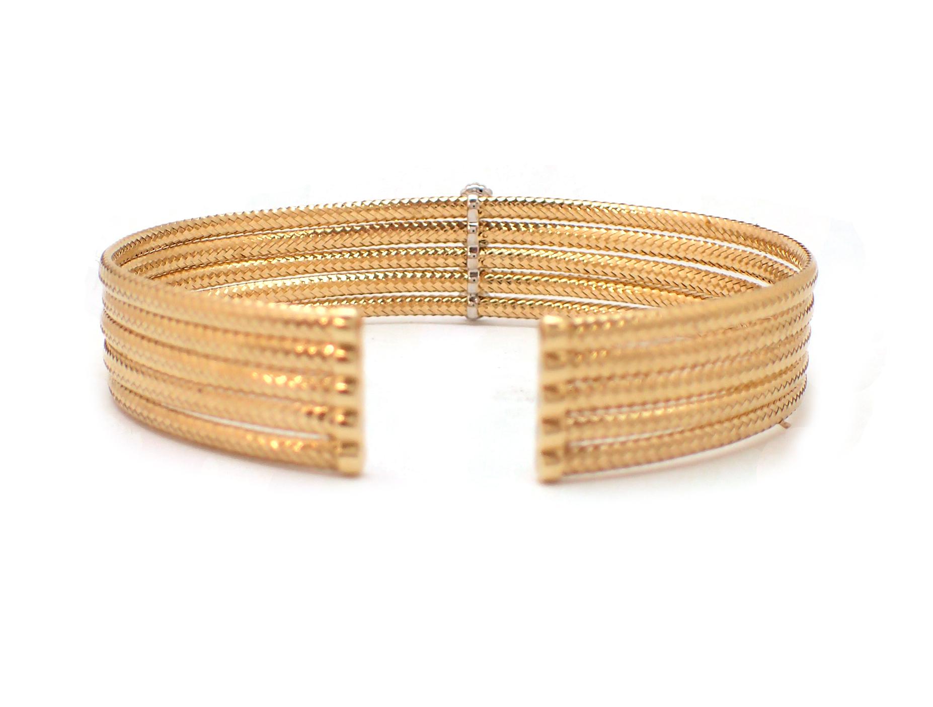 This fun and stylish flexible bangle bracelet features five 18 karat yellow gold woven rows, each punctuated with a diamond cluster. Made to fit just about any woman's wrist, it's easy to get on and off. This bangle contains 28 round brilliant