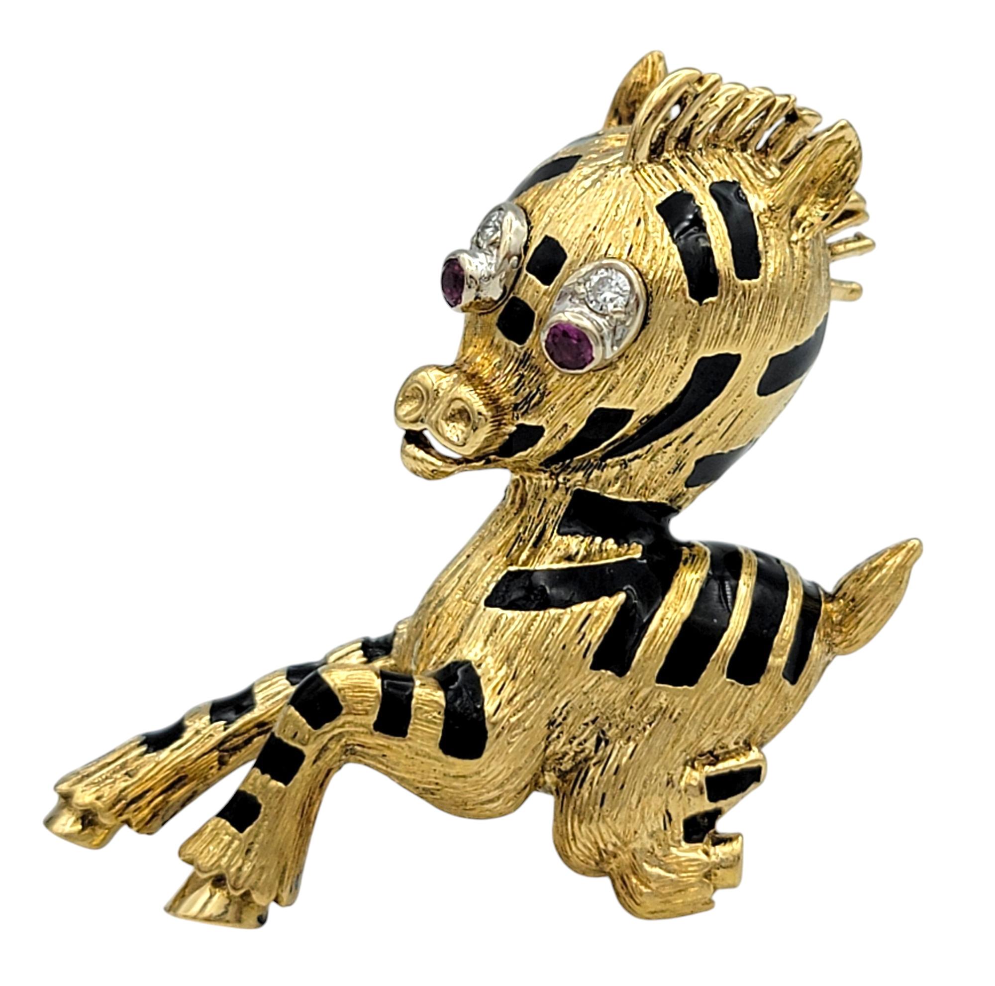 Réalisée en or jaune 18 carats, cette ravissante broche en forme de zèbre capture le mouvement et le charme avec son motif ludique en forme de saut. La pièce est ornée de bandes d'émail noir, créant un contraste saisissant avec l'or chaud. Ses yeux