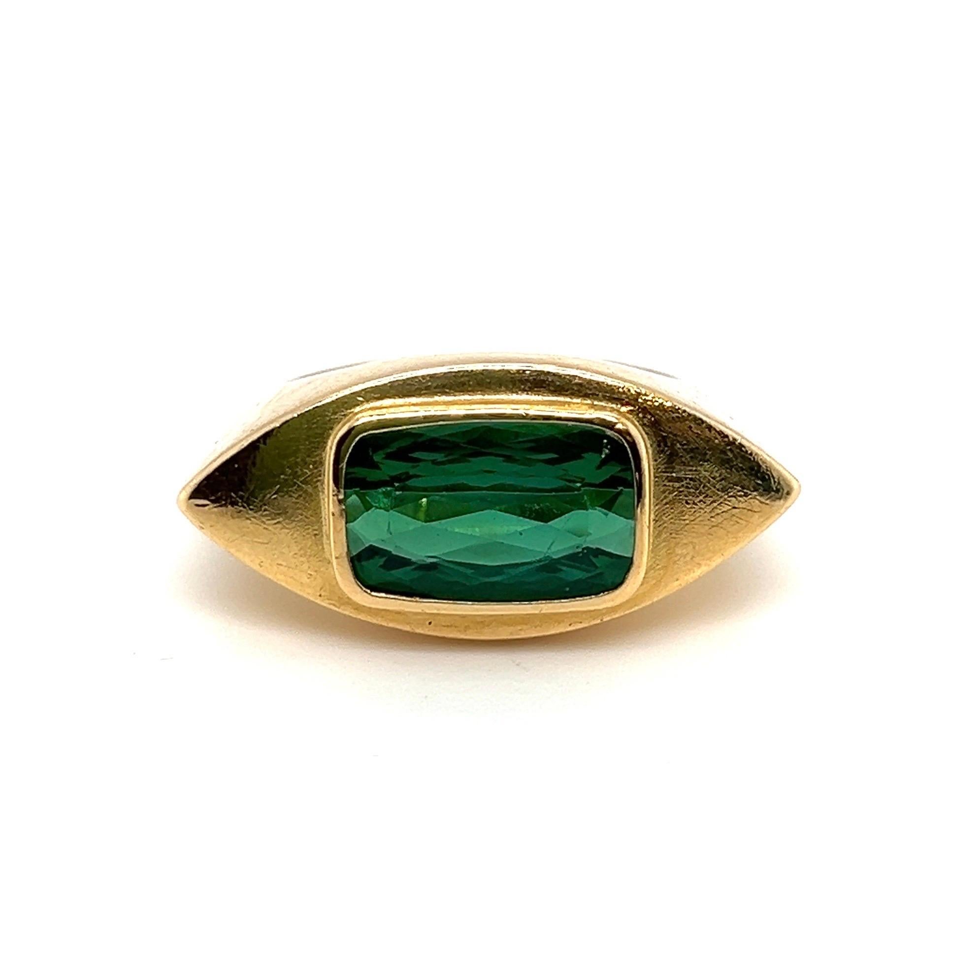 Ravishing 18 karat yellow gold and green tourmaline cocktail ring.

Ring of geometric design crafted in 18 karat yellow gold. The matte-finish, navette-shaped front is set with a luminous green, cushion-shaped tourmaline of ca. 3.5 carats.

This