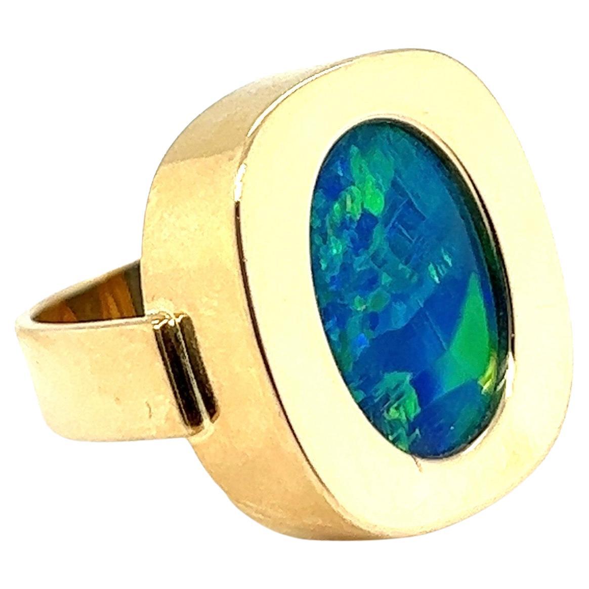Fabulous 18 karat yellow gold and opal Cocktail ring, 1970s.

Crafted in 18 karat polished yellow gold, the cushion-shaped ring head set with a beautiful oval opal doublet of circa 1.4 x 1.0 cm / 0.55 x 0.39 in. The opal displays a very lively blue