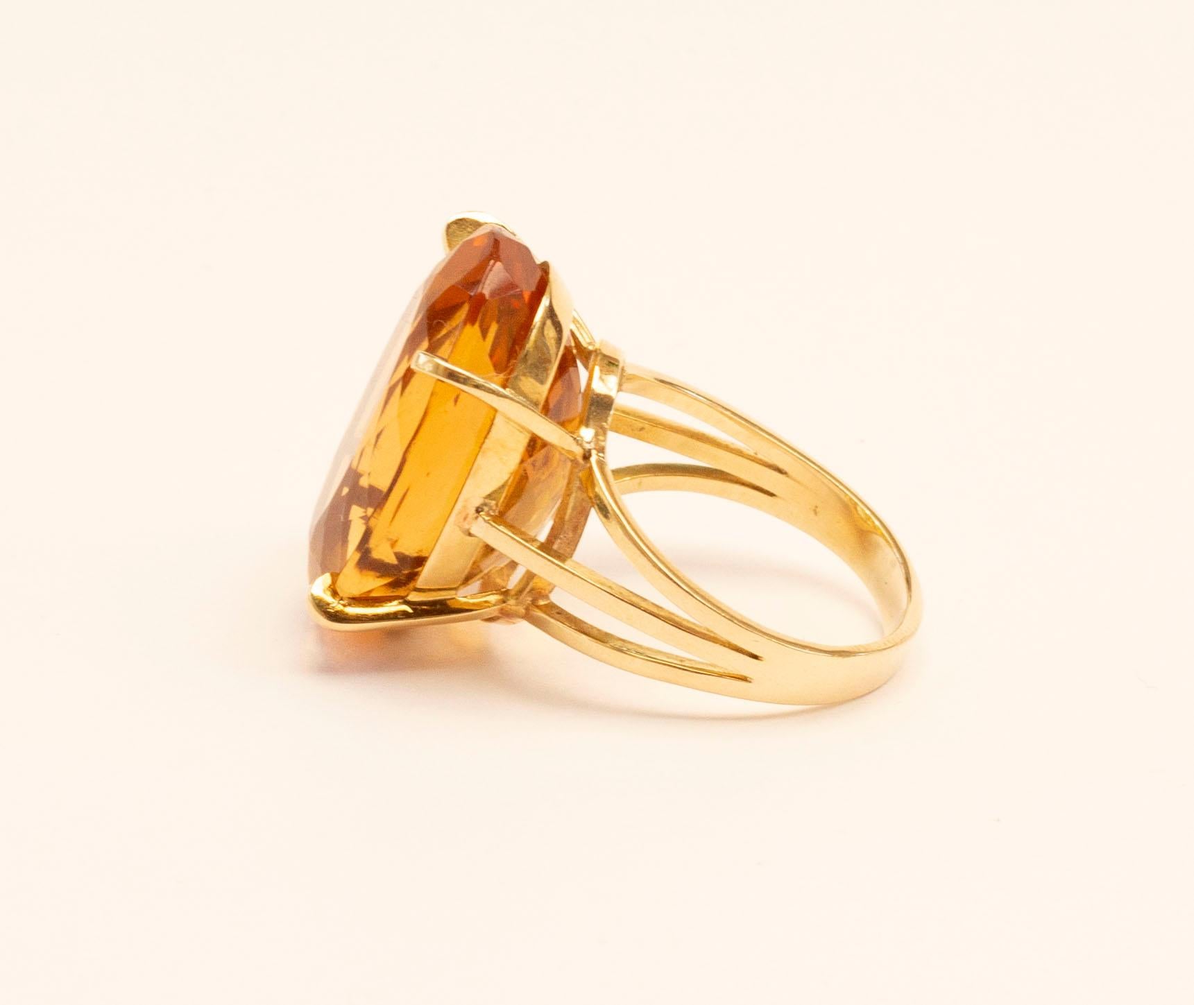A vintage (1970s) 18 Karat yellow gold cocktail ring with a large oval brilliant cut citrine in a classic yellow gold mount. The ring is not marked for the gold content and the manufacturer's name. The ring was professionally tested for the gold