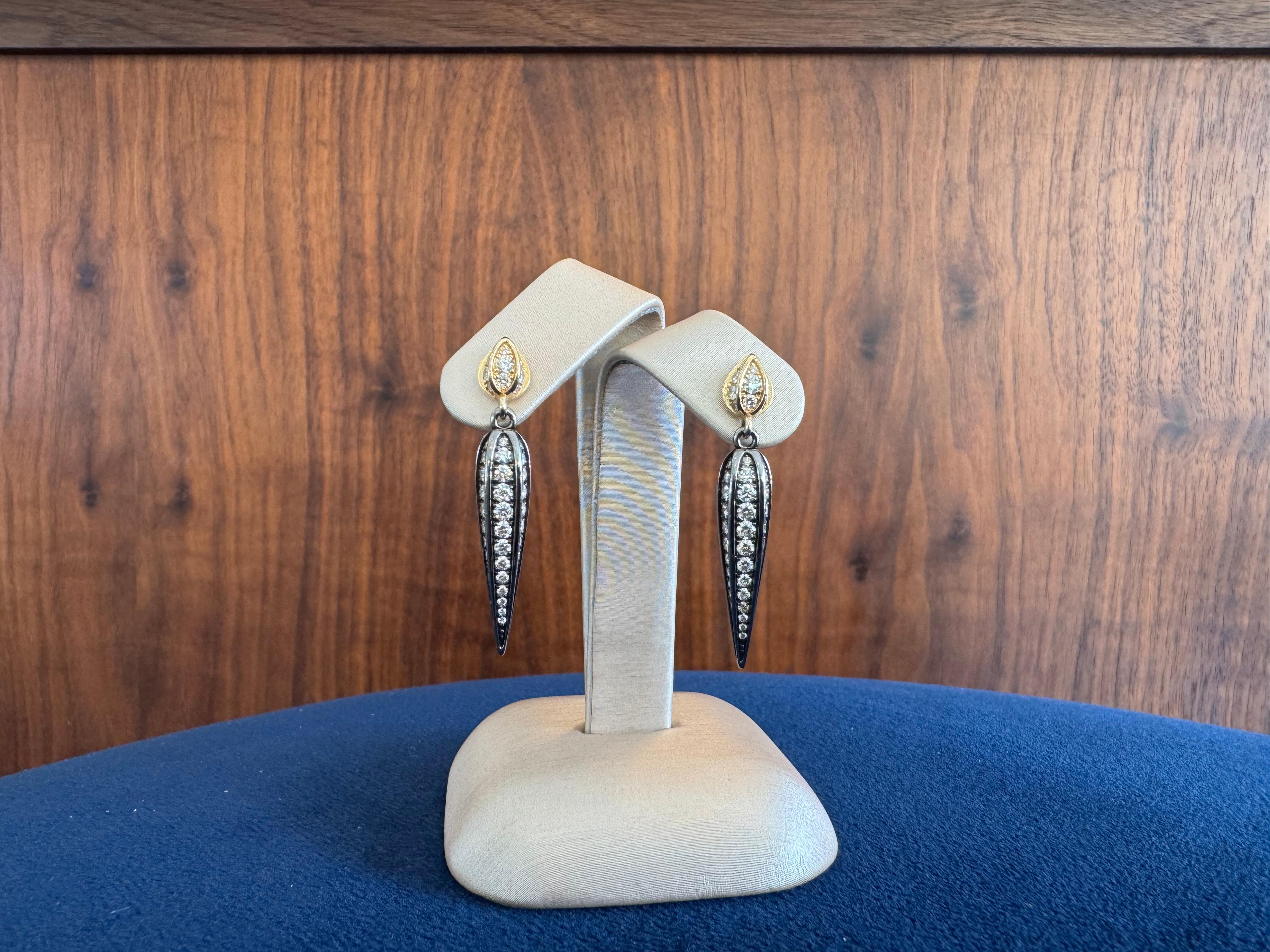 Ces boucles d'oreilles pendantes sont un parfait mélange de nature et de luxe. Réalisées en or jaune 18 carats et en argent oxydé de haute qualité, ces boucles d'oreilles sont conçues pour capturer l'élégance délicate d'une feuille. L'argent oxydé