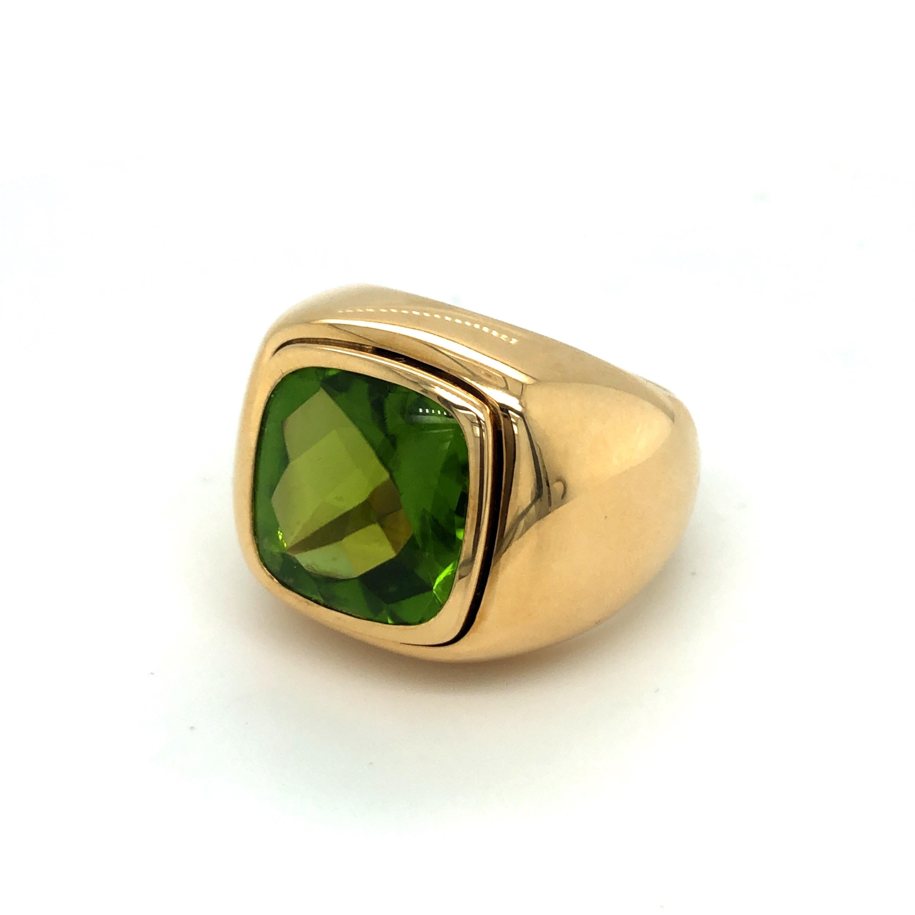 Impressive 18 karat yellow gold and peridot signet ring by the renowned Swiss jeweler Bucherer.
This statement ring is set with a vivid green peridot of 13.3 carats featuring a polished upper side and a faceted back side providing lively light