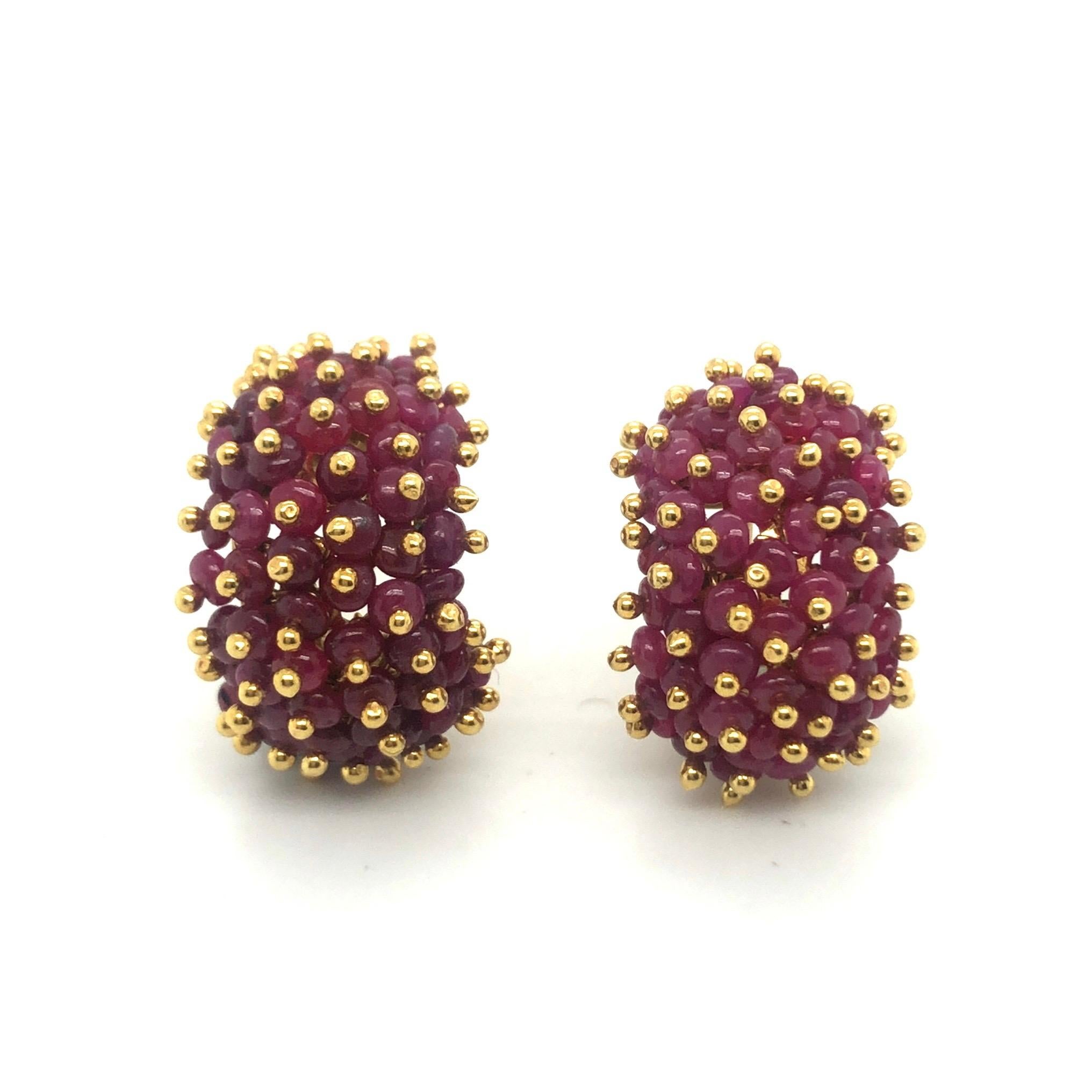 Captivating 18 karat yellow gold and rubies earrings, circa 1960s.
Designed as domed half-hoop earclips, set with ruby beads totalling circa 10 carats and enhanced with gold beads. They are completed by hinged omega-backs and fine studs to provide