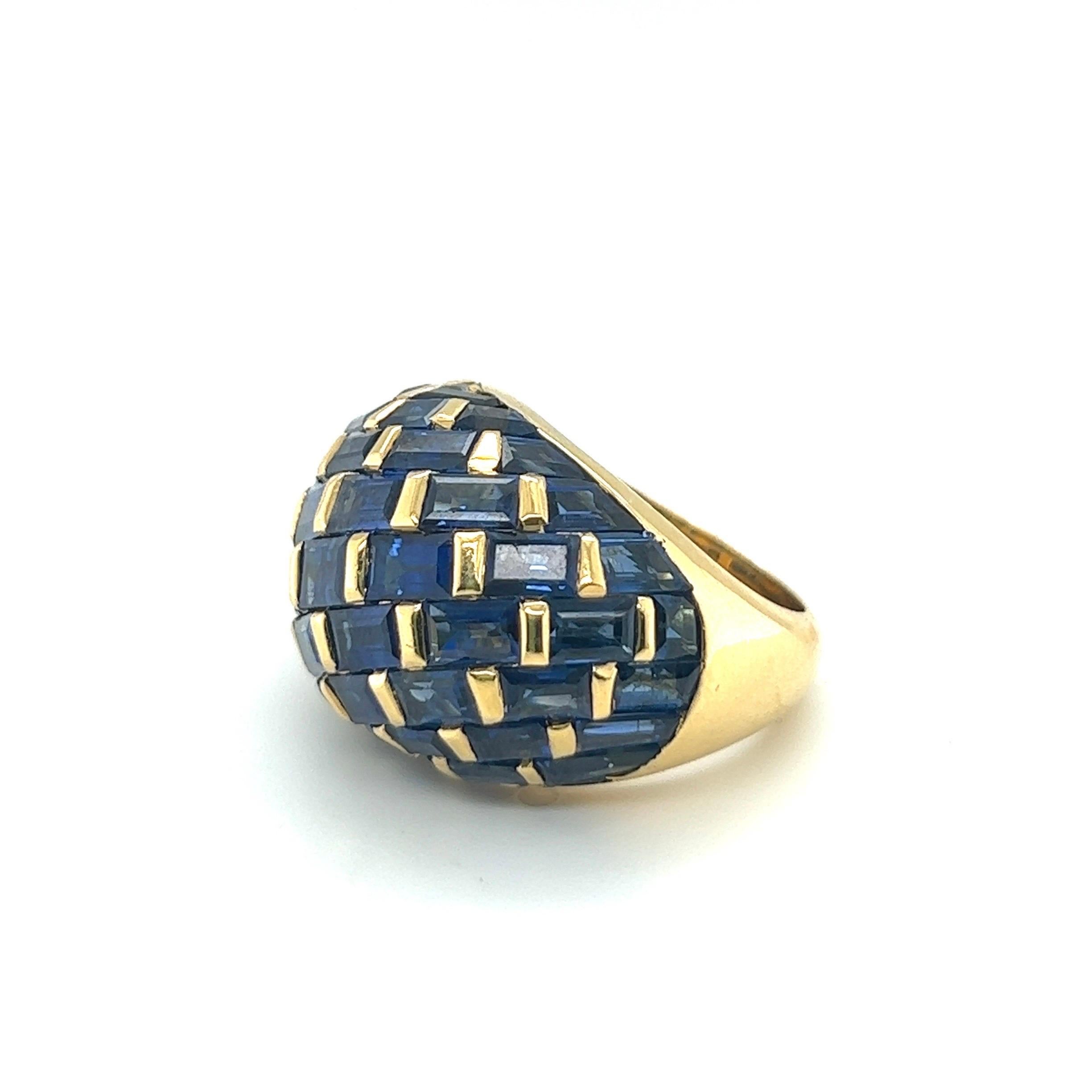 Ravishing 18 karat yellow gold and sapphire cocktail ring, circa 1970s.

Crafted in 18 karat yellow gold, of bombé design, the dome fully set with numerous sapphire baguettes and trapezes of a deep yet luminous blue shade. The way the sapphires are
