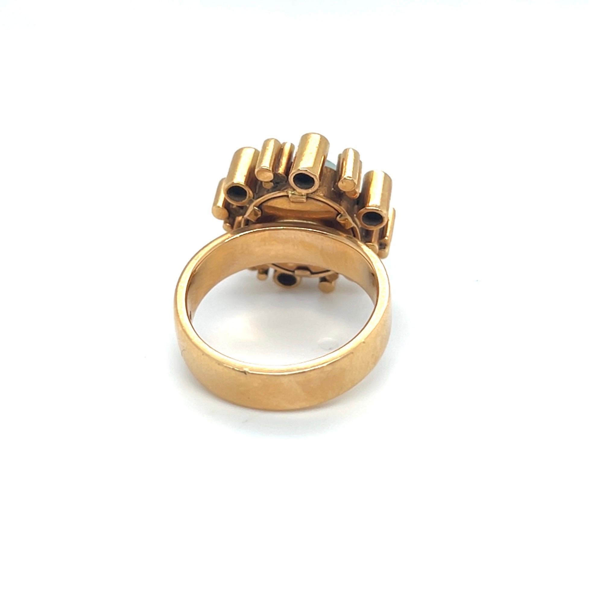 Llamativo anillo de c�óctel modernista de oro amarillo de 18 quilates y turmalina, años 70.

Magistralmente elaborado a mano en oro amarillo de 18 quilates, este deslumbrante anillo de cóctel está engastado con un cabujón redondo de turmalina verde