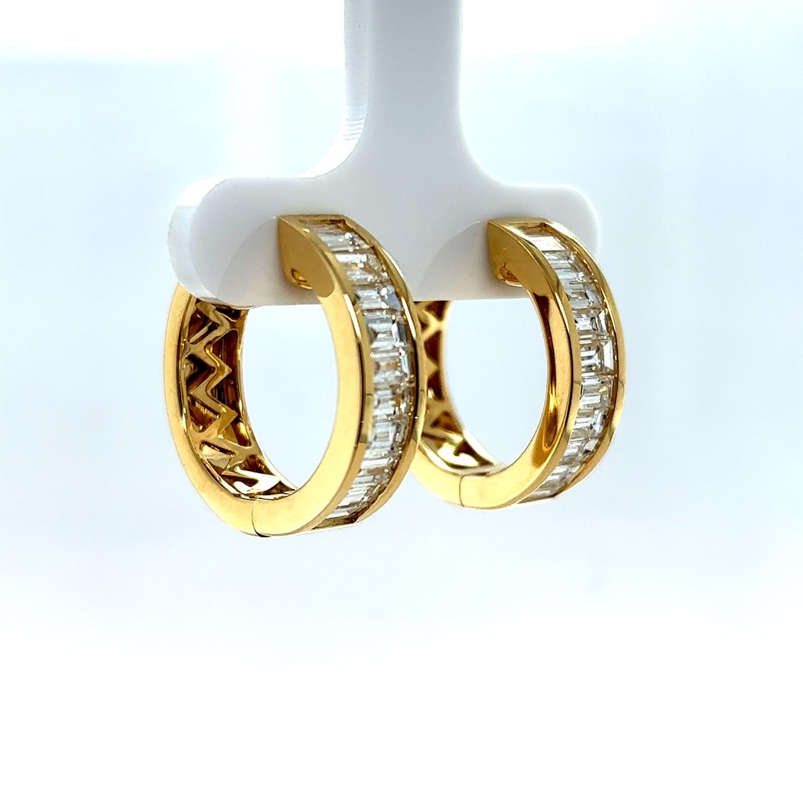 A pair of 18 karat yellow gold baguette cut diamond hoop earrings

This chunky wide pair of hoop earrings are channel set with baguette cut diamonds of 1.32 carats approximately, assessed as 
H/I colour, VS2-SI2 clarity.

The reverse of the yellow
